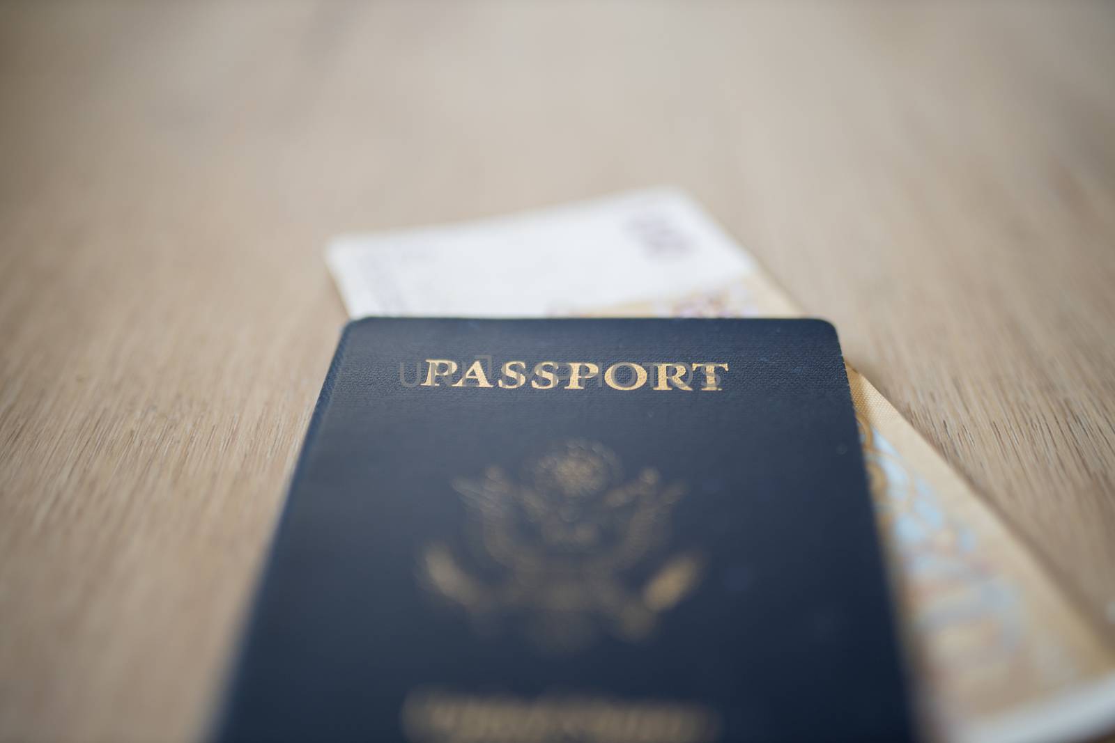 Picture of a blurry United States of America Passport with a blurry 100 Moroccan Dirhams Bill Partially Inside