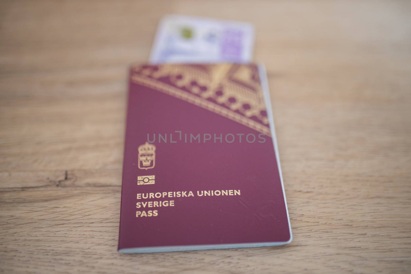 Picture of a Sweden Passport with a blurry 20 Swedish Kronor Banknote Partially inside