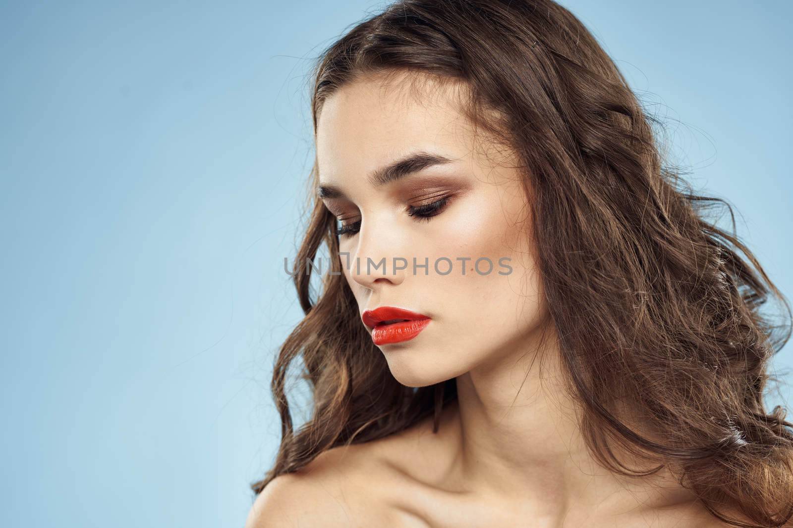 Brunette naked shoulders red lips fashionable hairstyle blue background. High quality photo