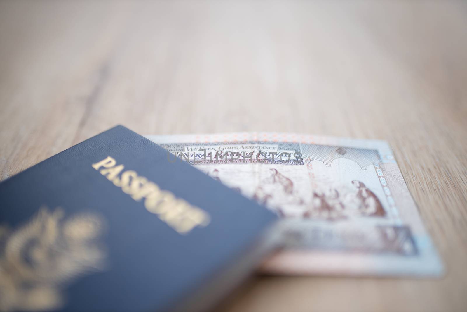 Picture of a Kuwait Quarter Dinar Partially Inside a blurry United States of America Passport