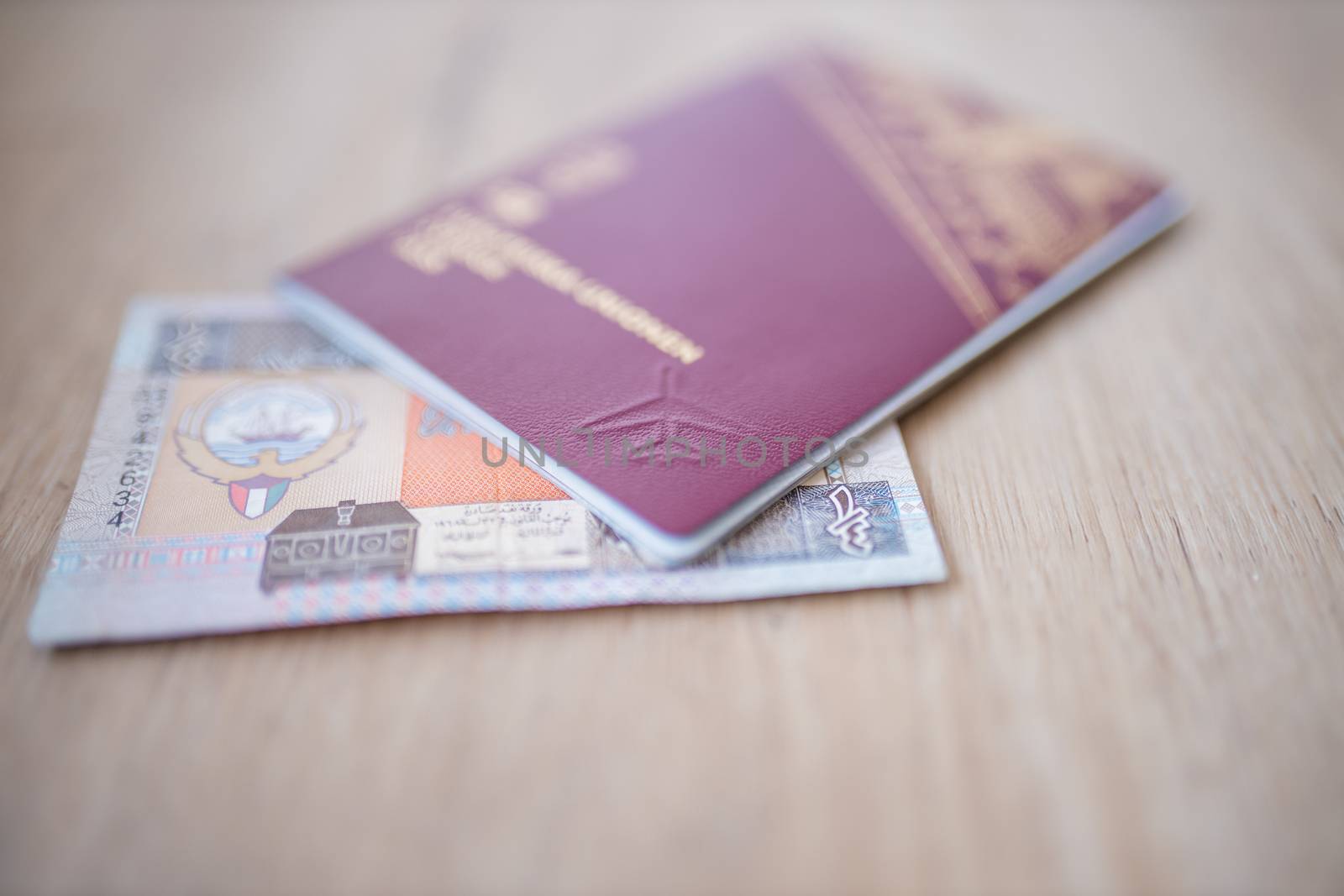 Picture of a Kuwait Quarter Dinar -with the numbers 1-fourth in Arab- Partially Inside a blurry Sweden Passport