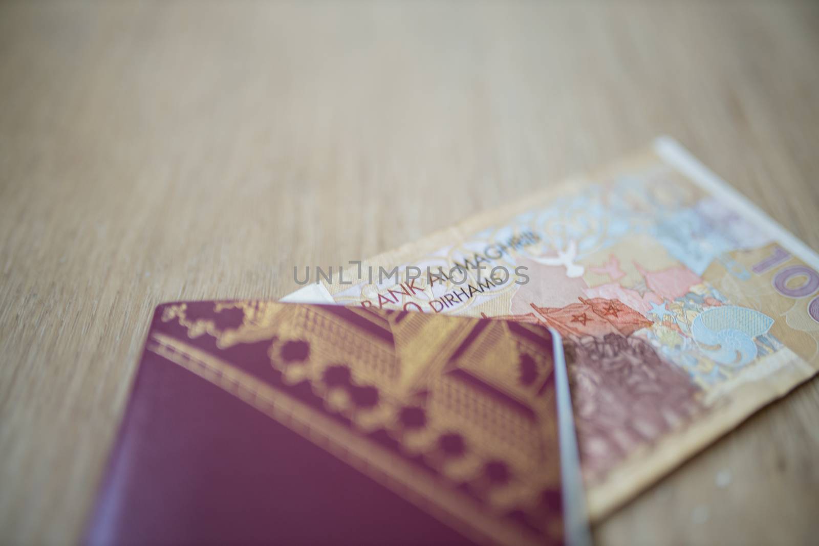 Picture of a 100 Moroccan Dirhams Bill Partially Inside a blurry Sweden Passport