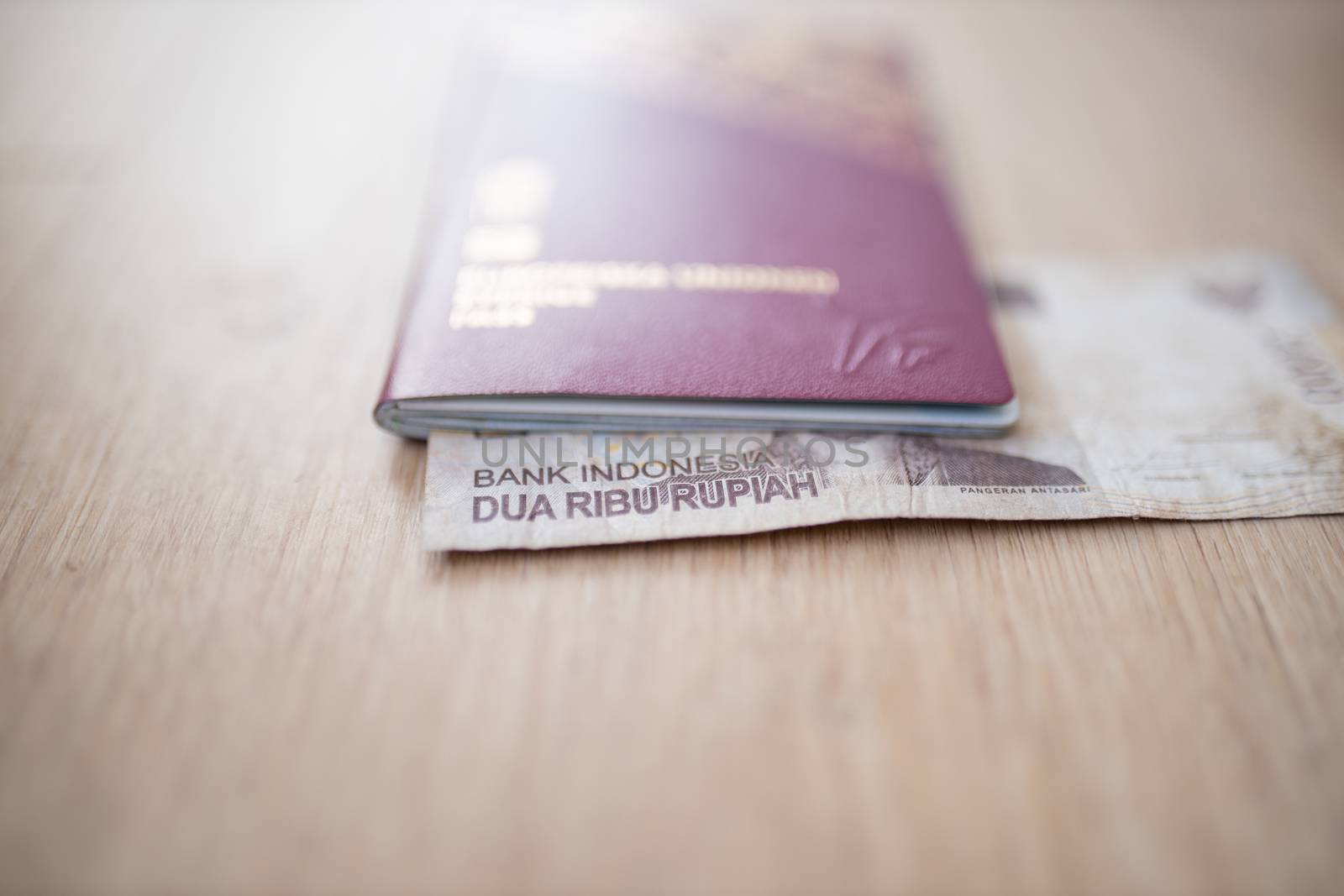 Picture of a 2000 Indonesian Rupees Bill -with the words Indonesia Bank and Two Thousand Rupees in Indonesian- Inside a blurry Sweden Passport