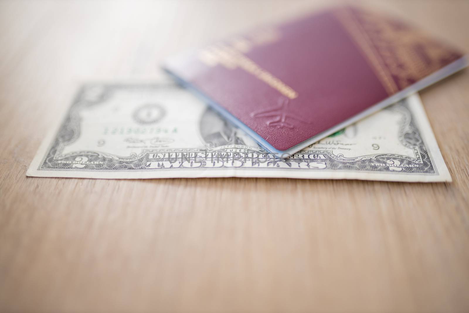Two-Dollar Bill Partially Inside a Blurry Sweden Passport on a Wooden Table