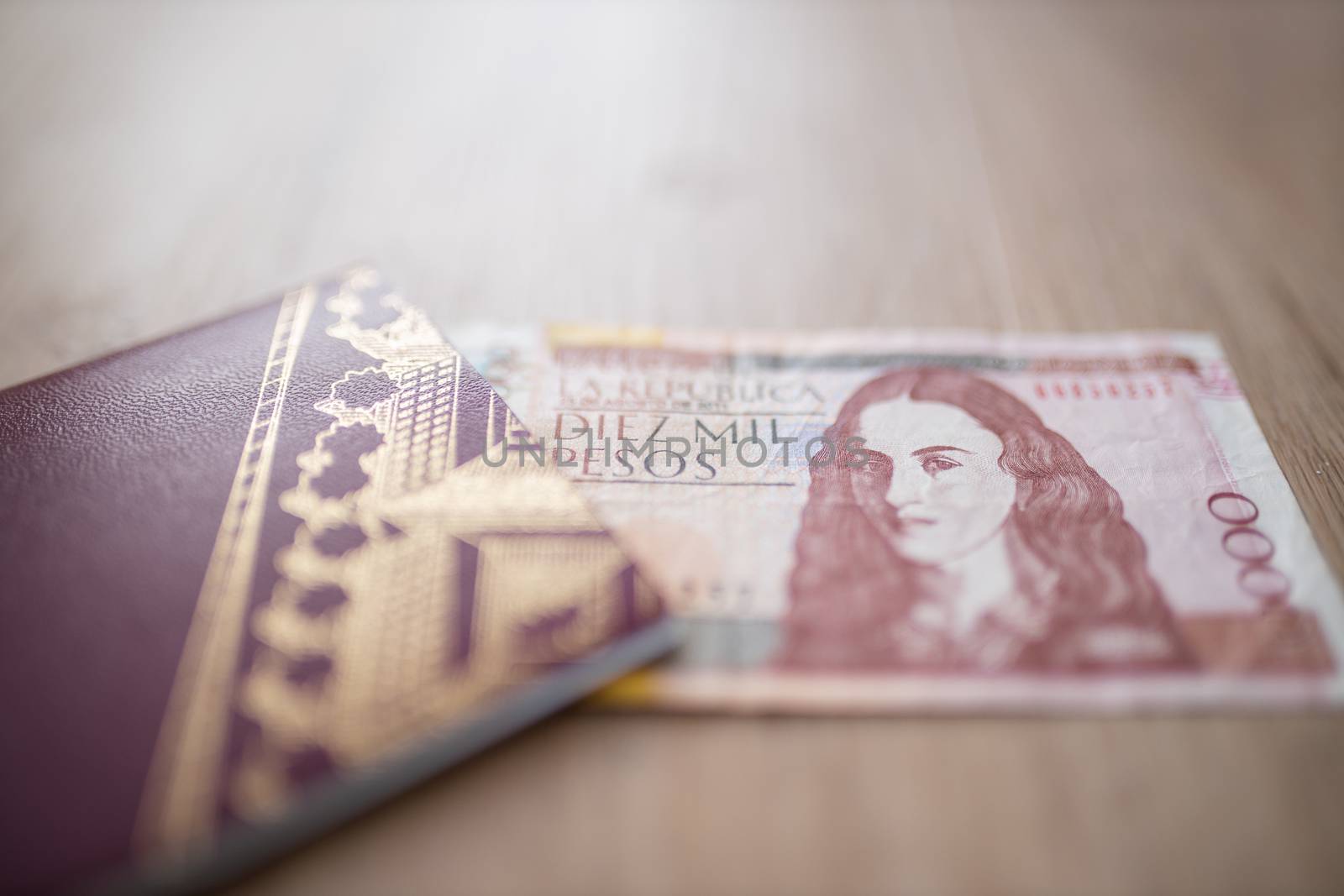 Picture of a Swedish Passport with half a 10.000 Colombian Pesos Bill Inside, showing the Face of Policarpa Salavarrieta