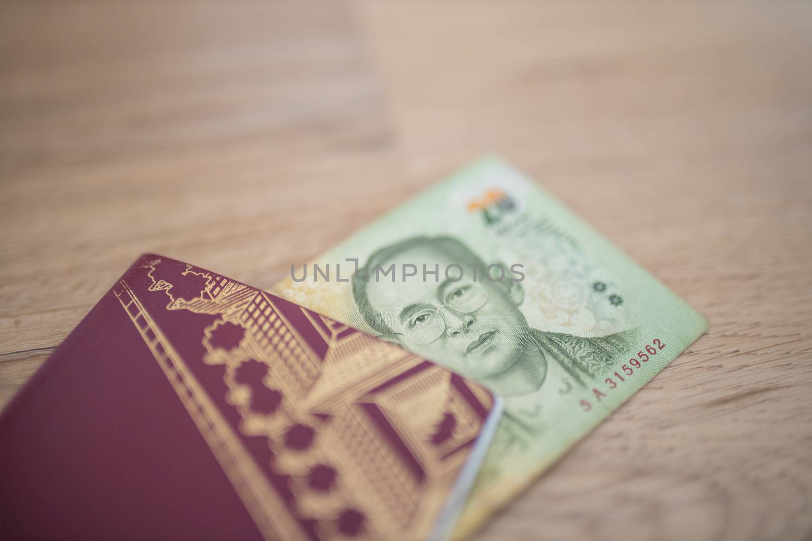 Picture of a 20 Thai Baht Bill Partially Inside a blurry Sweden Passport, showing the face of Bhumibol Adulyadej