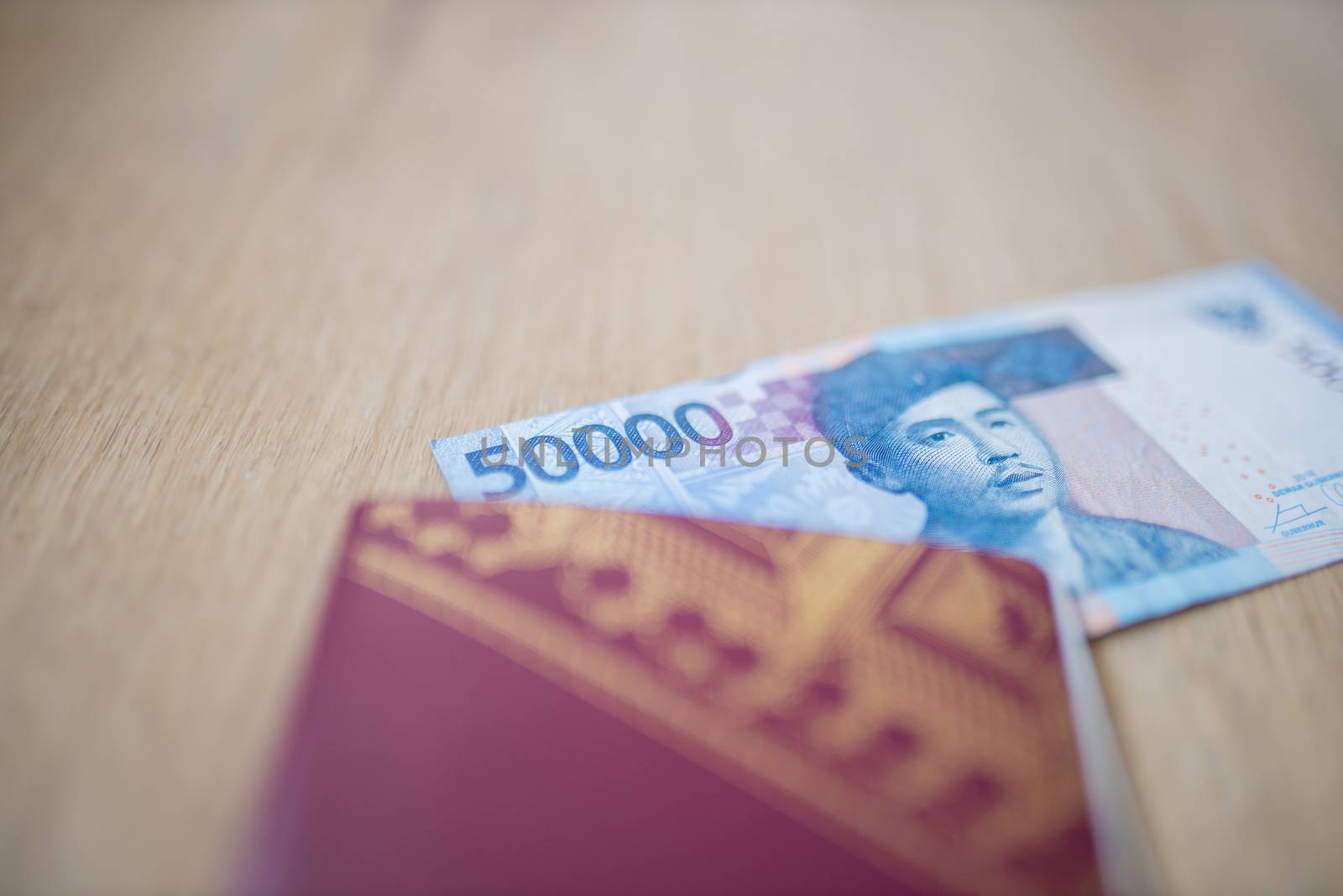 Picture of the corner of a Fifty Thousand Indonesian Rupees Bill partially inside a Swedish Passport