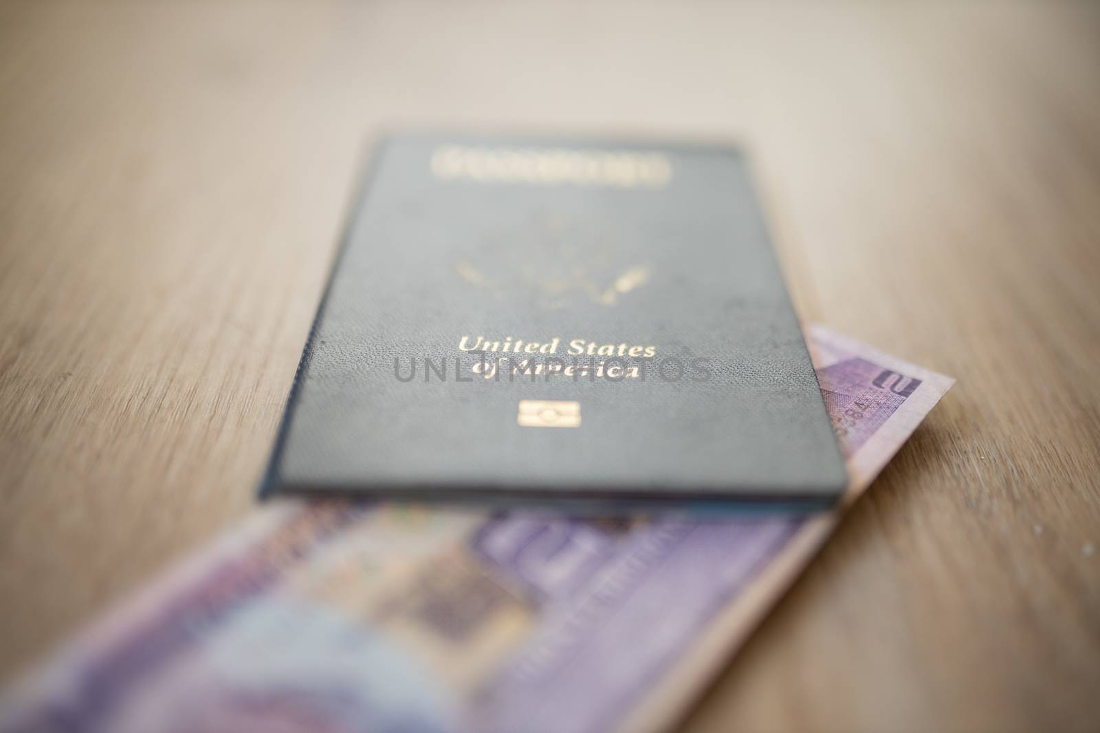 United States of America Passport with a Blurry Two Honduran Lempiras Bill under it, and both on a wooden table