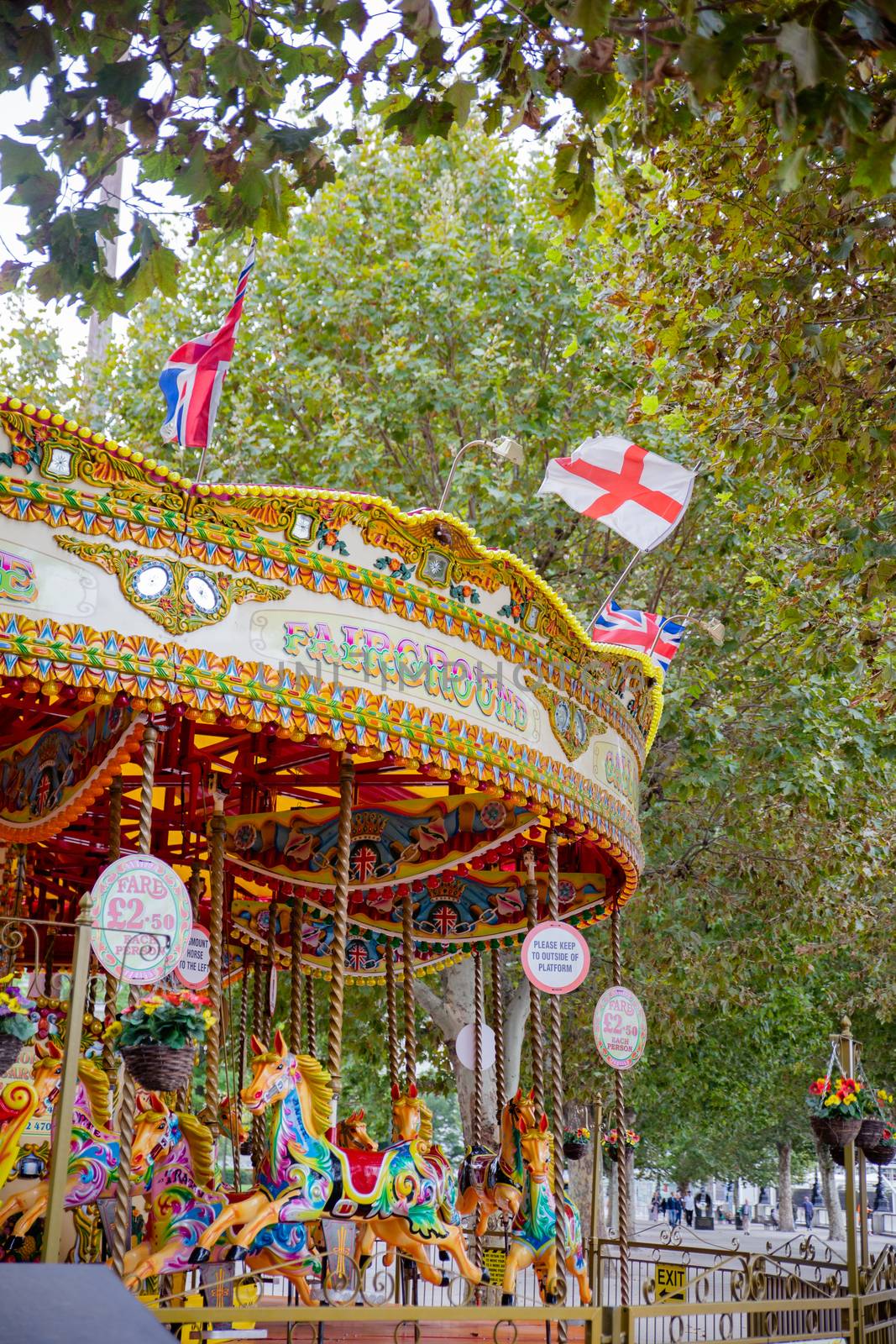 Portrait View of a Colorful Child Carousel Surrounded by the Trees of a Park from London, UK