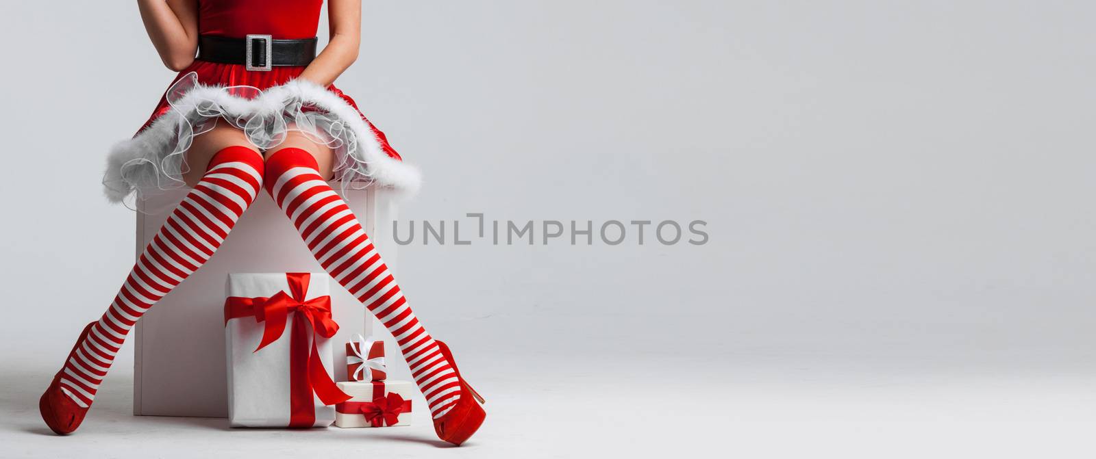 Beautiful Christmas pinup girl with gift boxes on white background with copy space