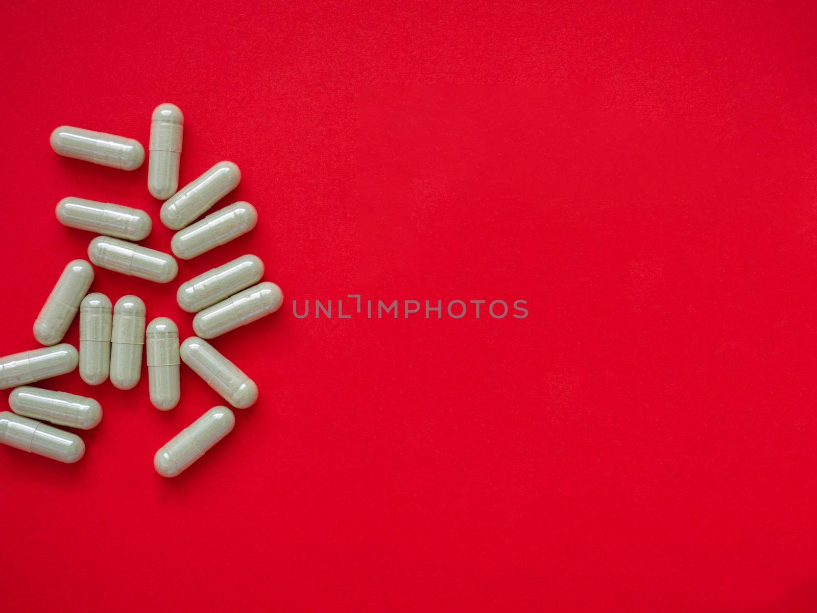 Gray pills for the treatment of body disorders are arranged on a red background