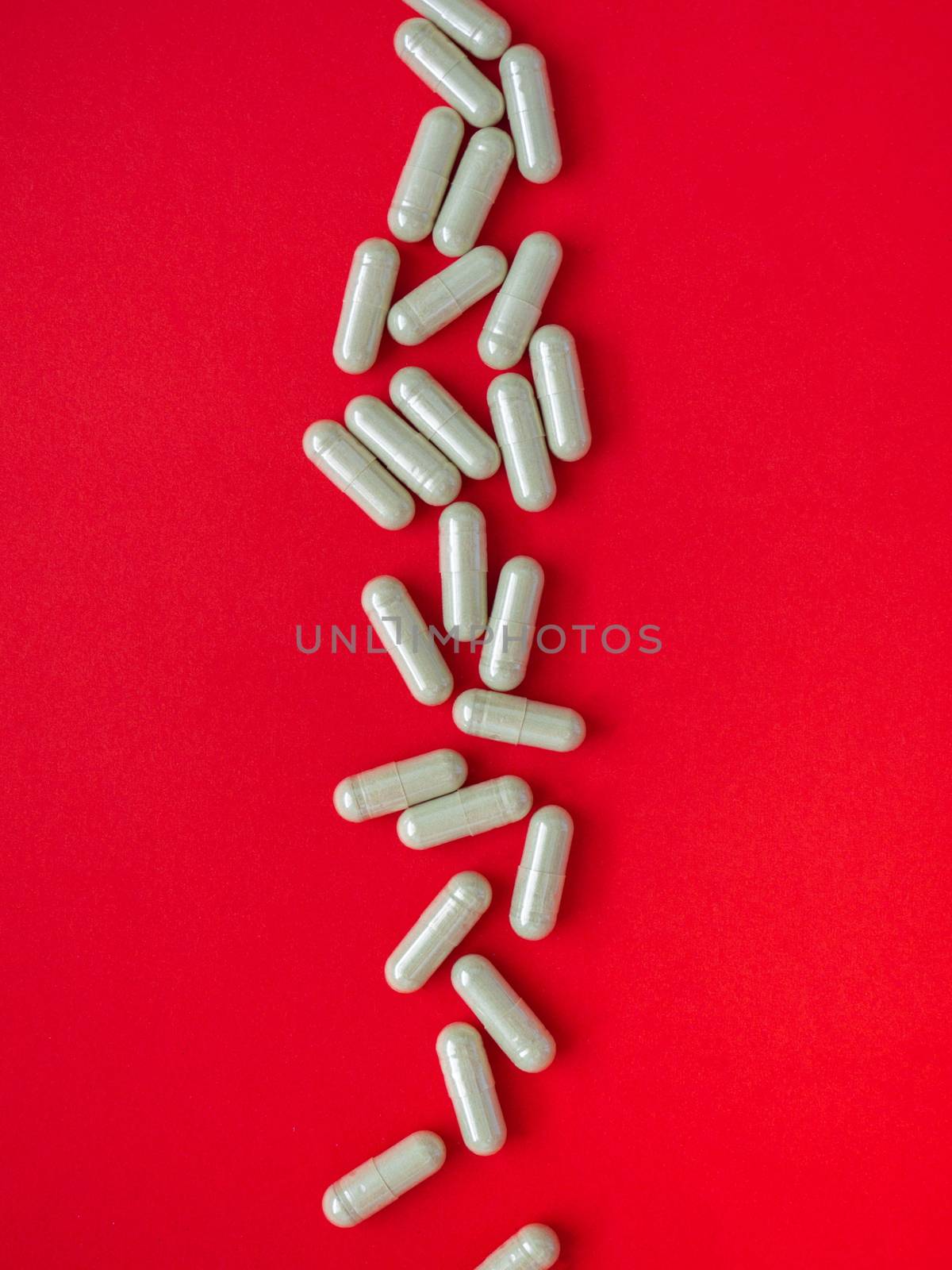 Gray pills for the treatment of body disorders are arranged on a red background