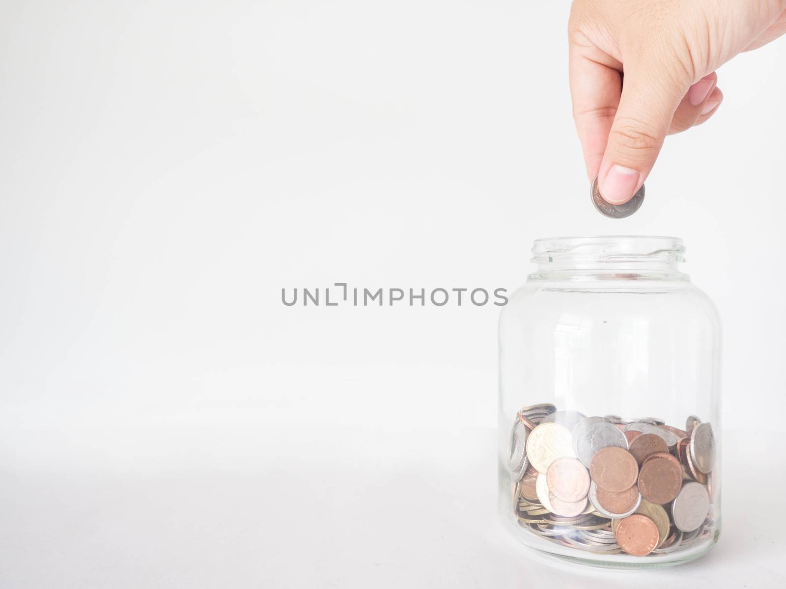 Man's hand is holding money into a jar to save money To save more money in the future. White background