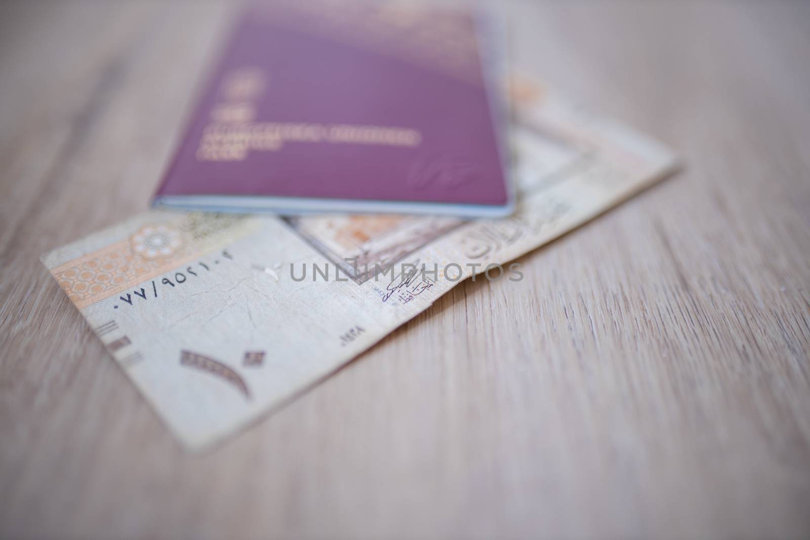 Picture of a Ten Saudi Riyals Bill -with the number 10 in Arabic- Partially Inside a blurry Sweden Passport