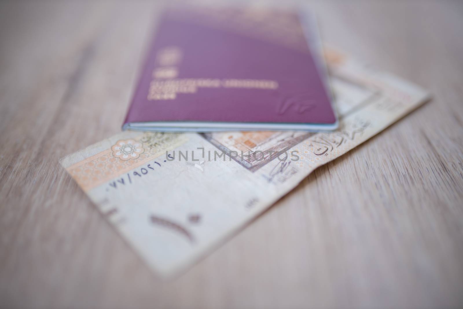 Ten Saudi Riyals Bill -with the words Monetary Agency, and the number 10 in Arabic- Partially Inside a blurry Sweden Passport