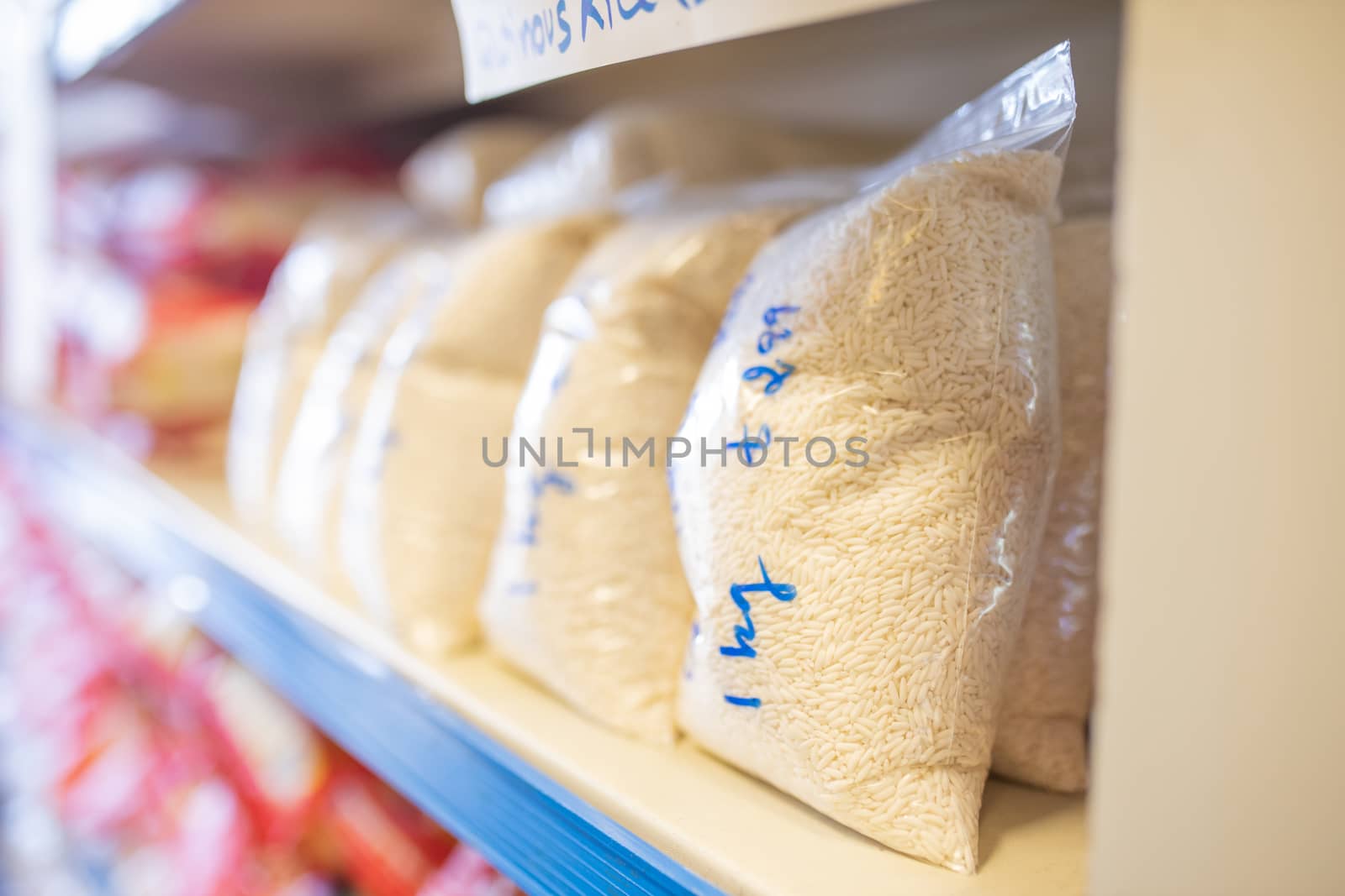 Picture of Rice Packed in Plastic Bags and on a Shelf Ready for Sale with prices written on the bags