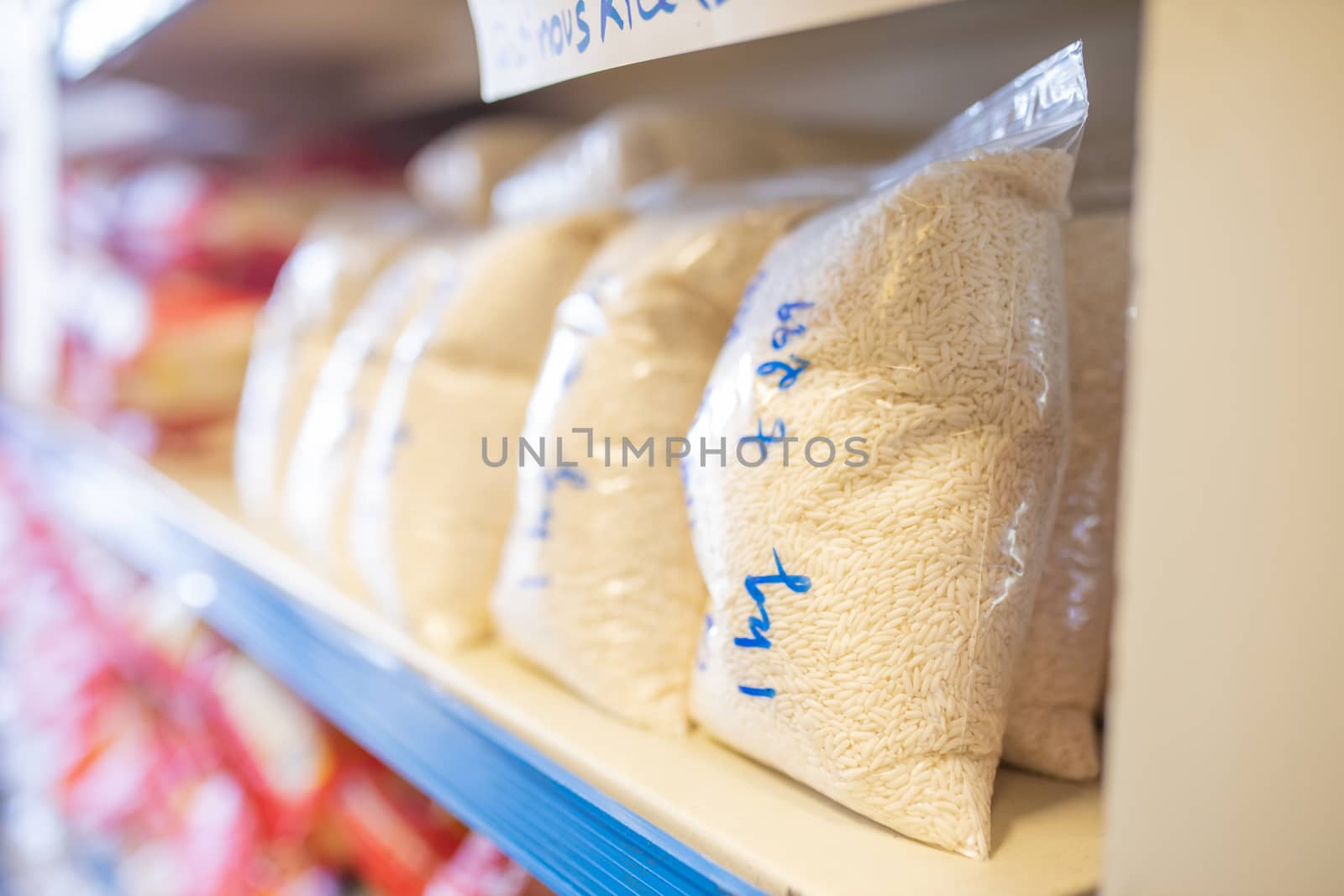 Picture of Rice Packed in Plastic Bags and on a Shelf Ready for Sale with prices written on the bags