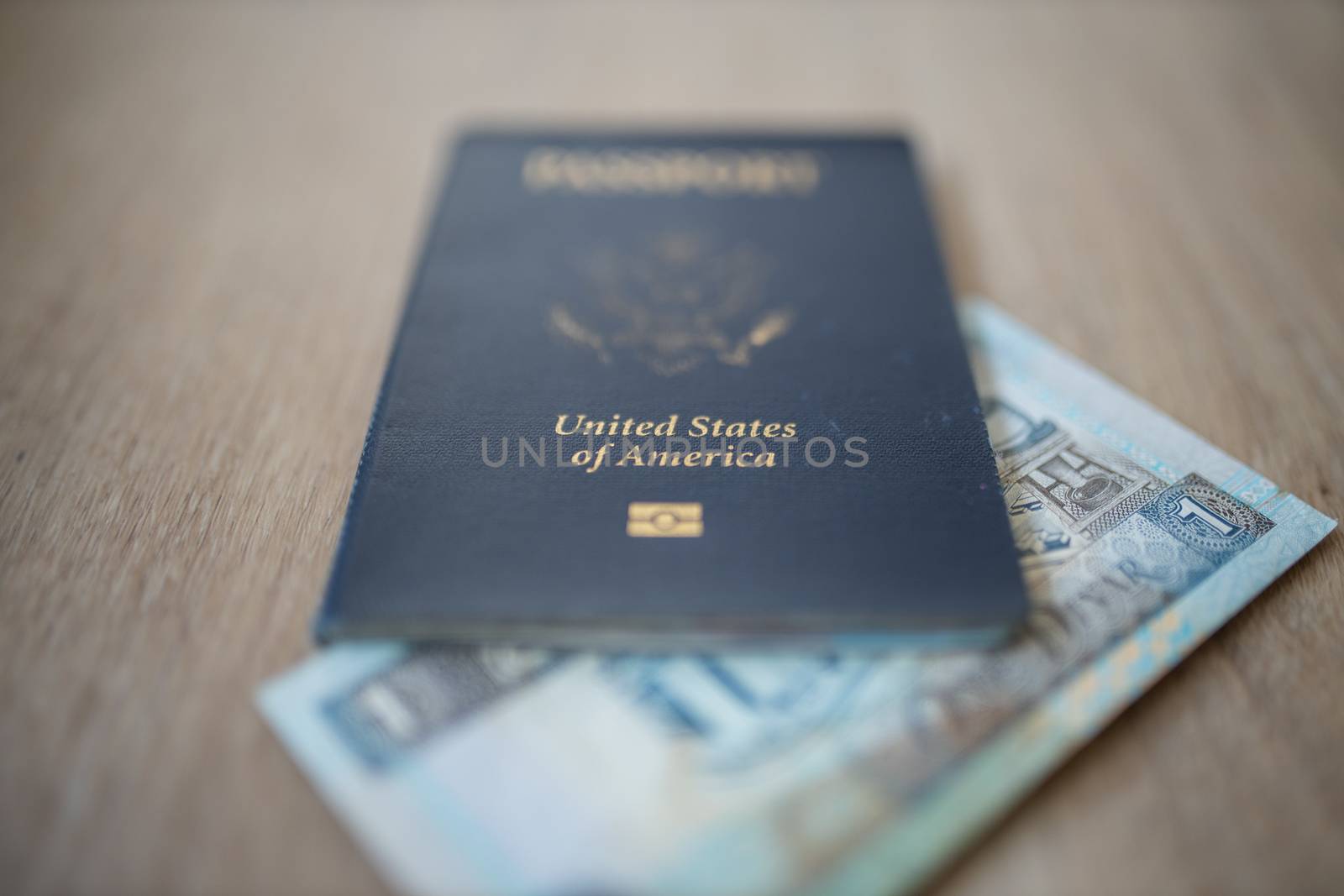 Picture of a blurry One Kuwaiti Dinar Bill Partially Inside a United States of America Passport