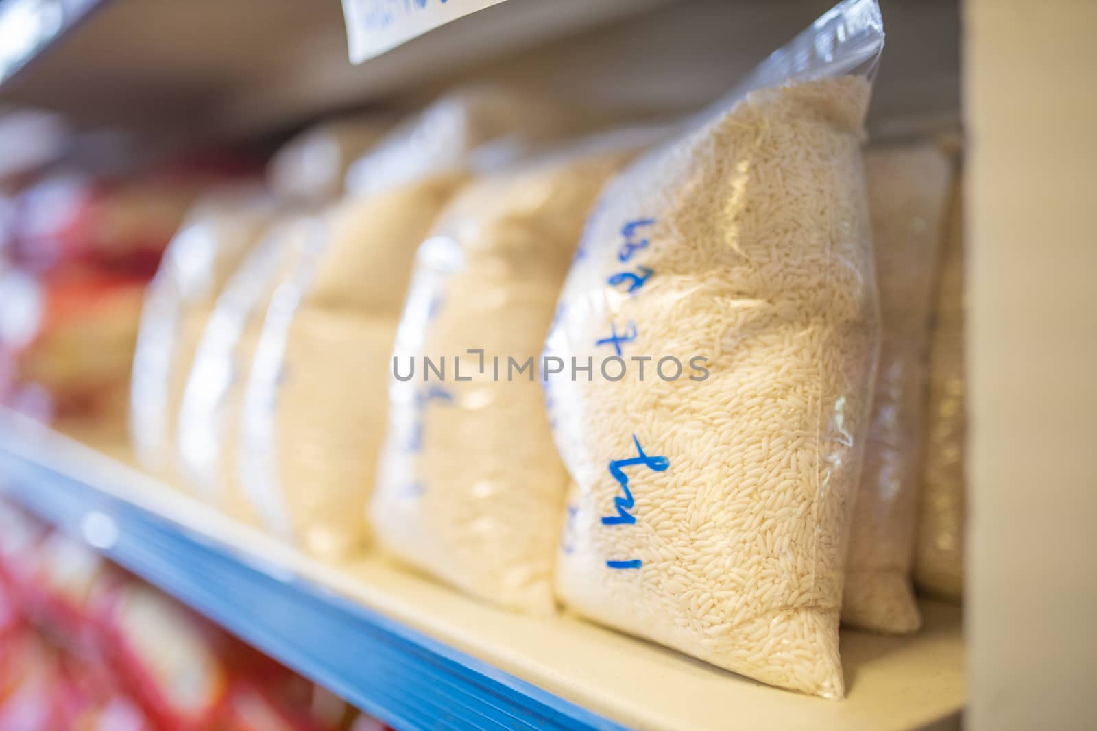 Picture of Rice Packed in Plastic Bags and on a Shelf Ready for Sale with prices written on the bags