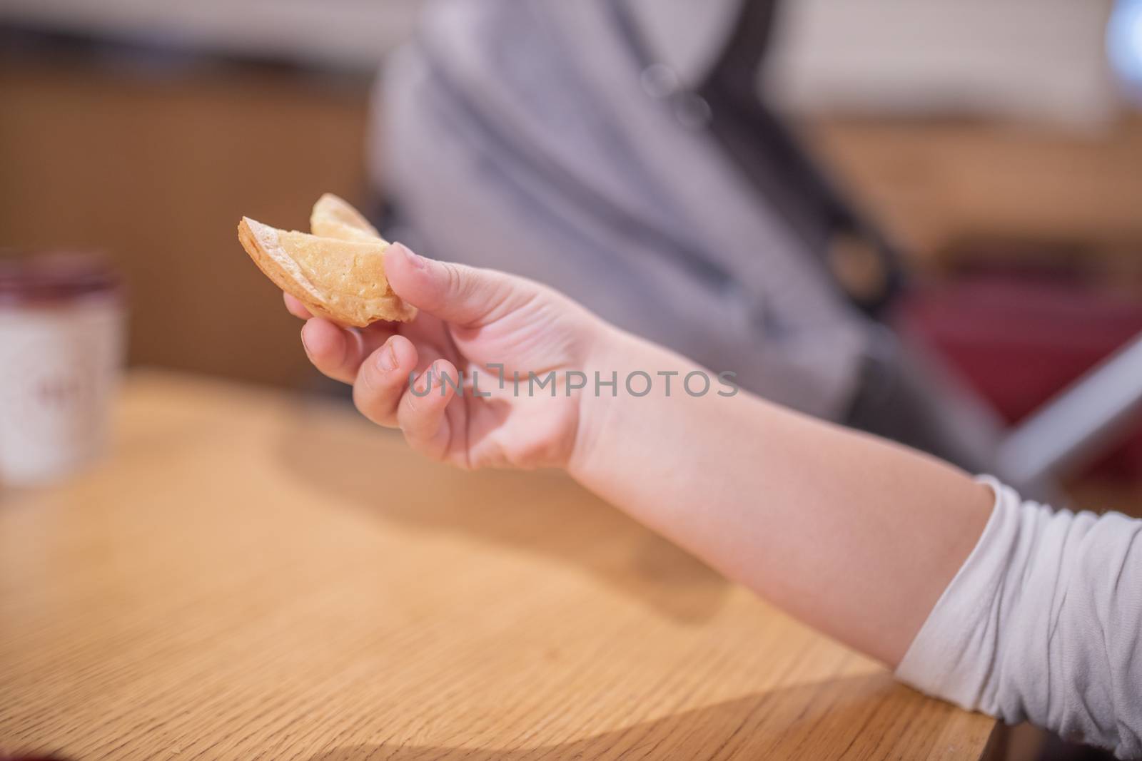 Picture of The Hand of a Little Girl Holding a Furtune Cookie with a Blurry stroller as background