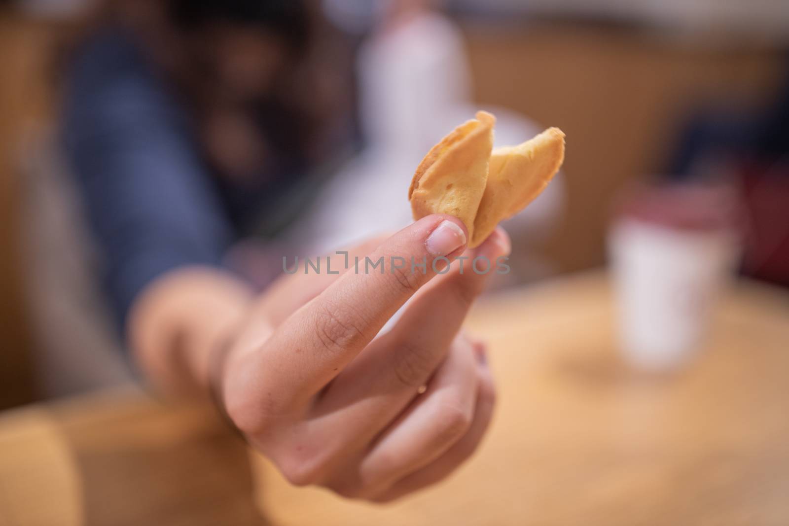 Picture of The Hand of a Woman Showing a Furtune Cookie Directly at the Camera, with a Blurry background