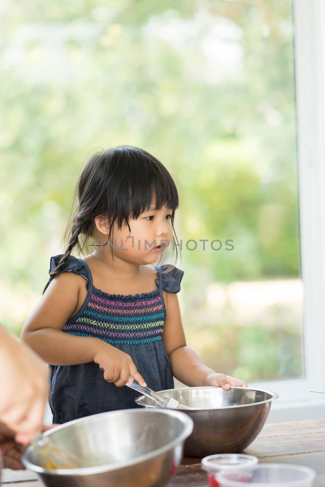 Asian little girl cooking something in kitchen by domonite