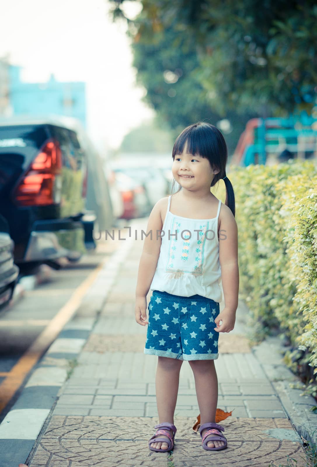 portrait of happy little girl standing in the park by domonite