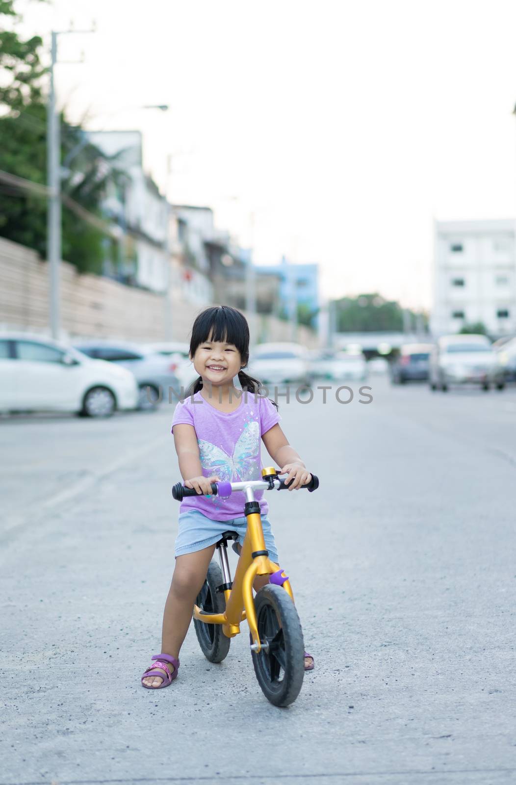 Little girl learns to riding balance bike on the road