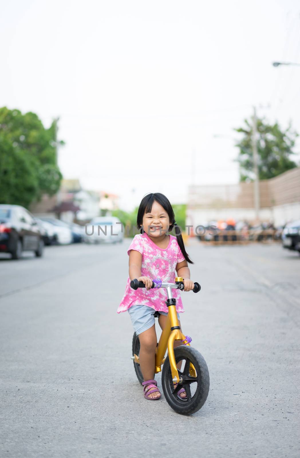 Little girl learns to riding balance bike on the road by domonite