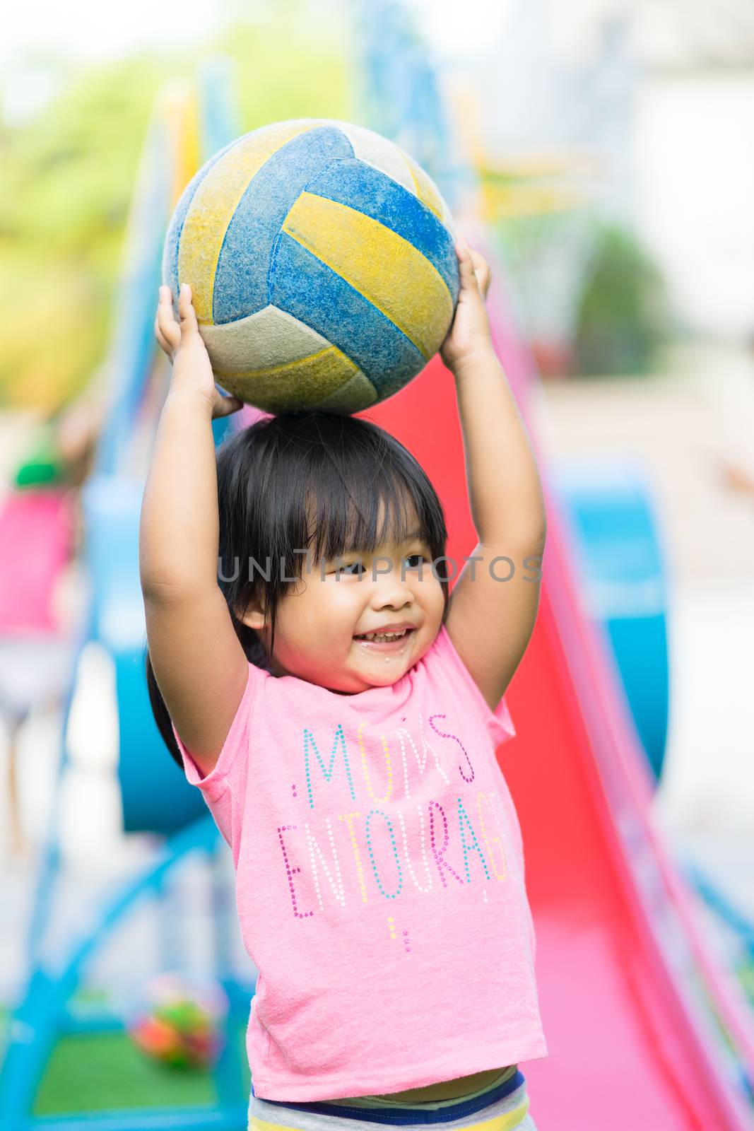 Asian little girl enjoys playing ball in a children playground by domonite