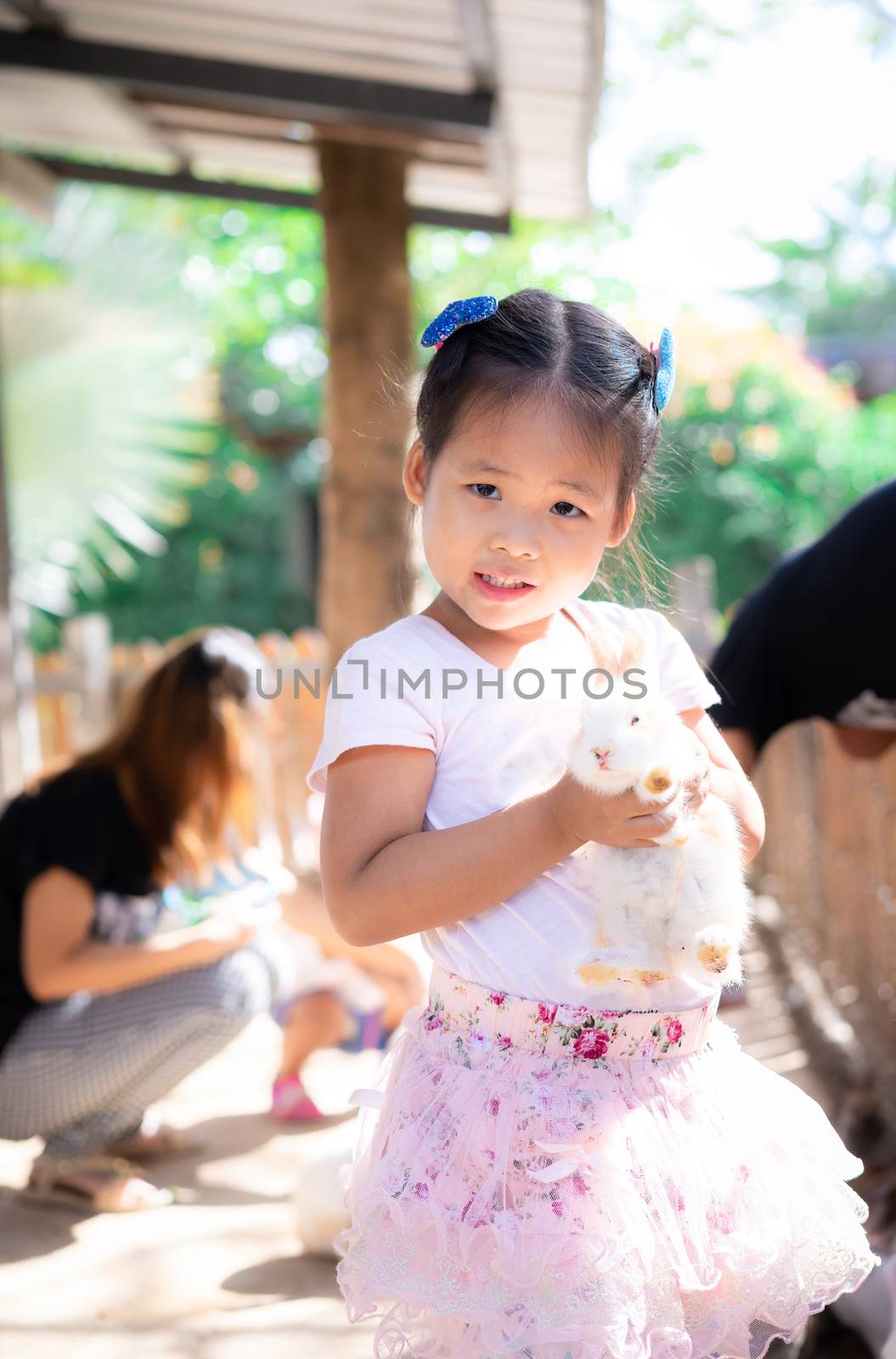 Cute little girl holding rabbit on the farm