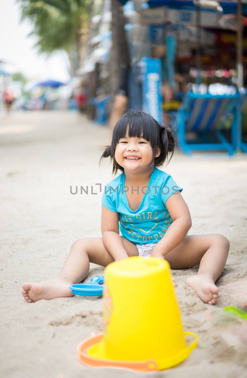 smiling little girl playing sand on the beach