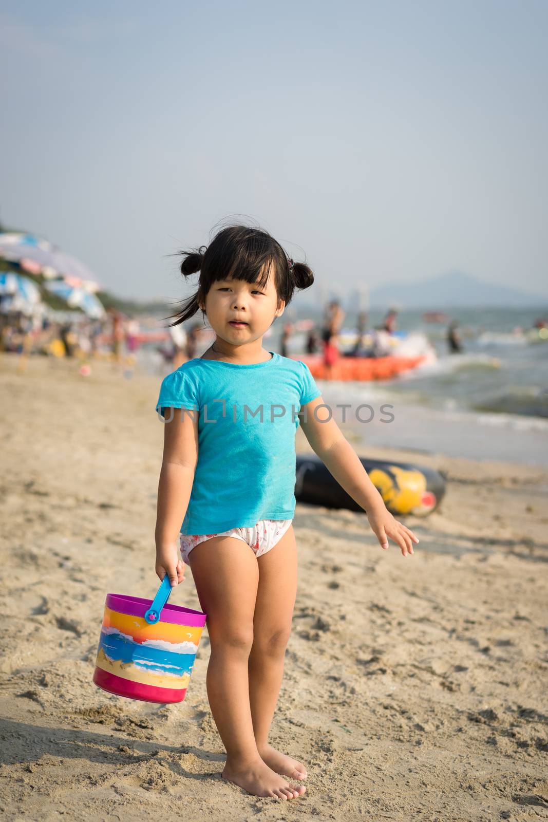 little girl holding a bucket for playing sand on the beach