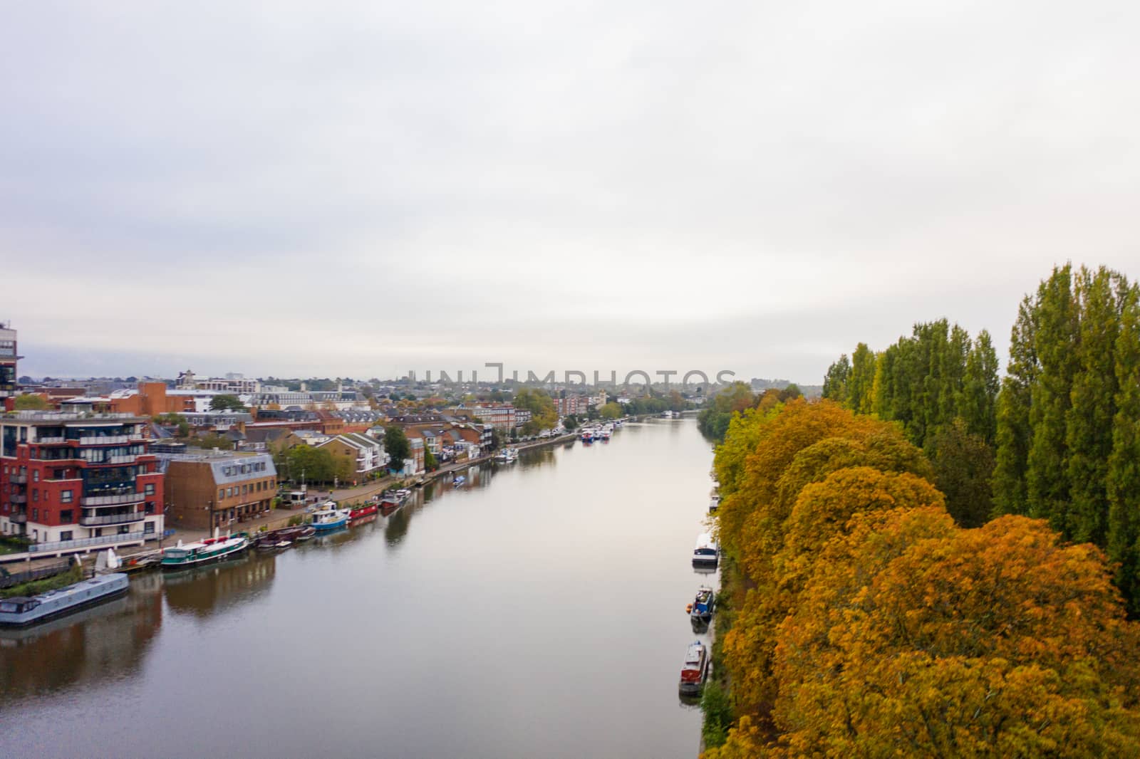 Aerial Landscape Picture of a Cloudy Skyline Over a River that Divides a Town and a Small Forest