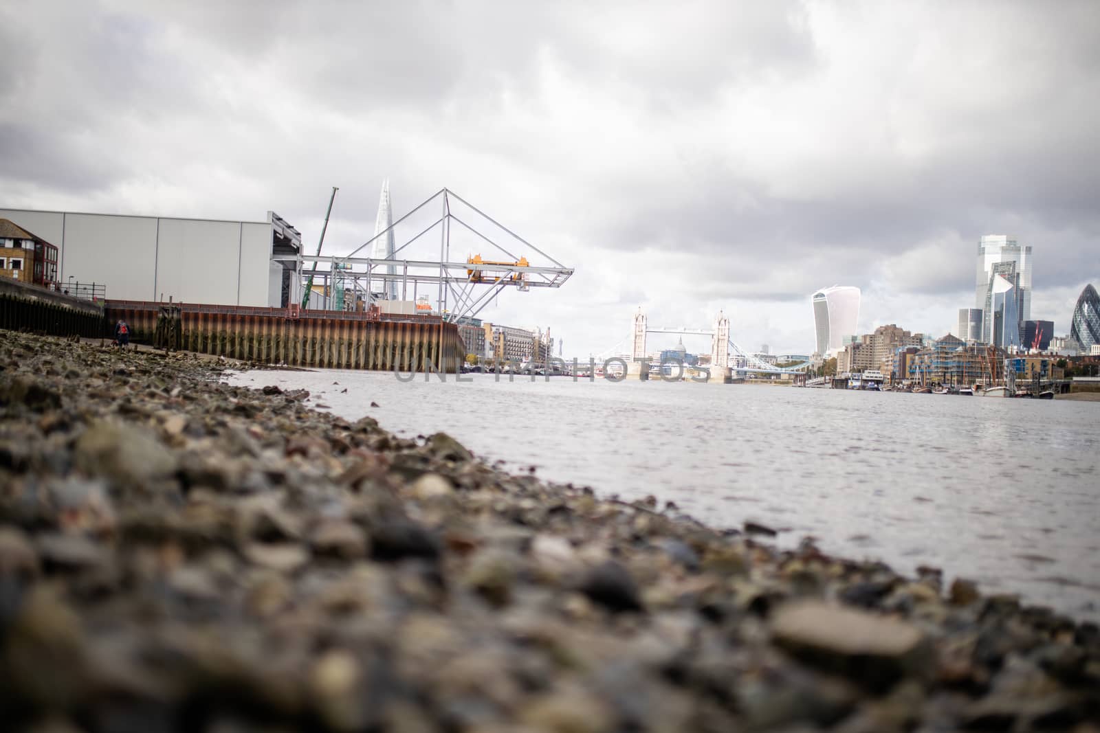Landscape View of a Cityscape and the Tower Bridge from the Rocky Ground Alongside the River Thames in London, UK