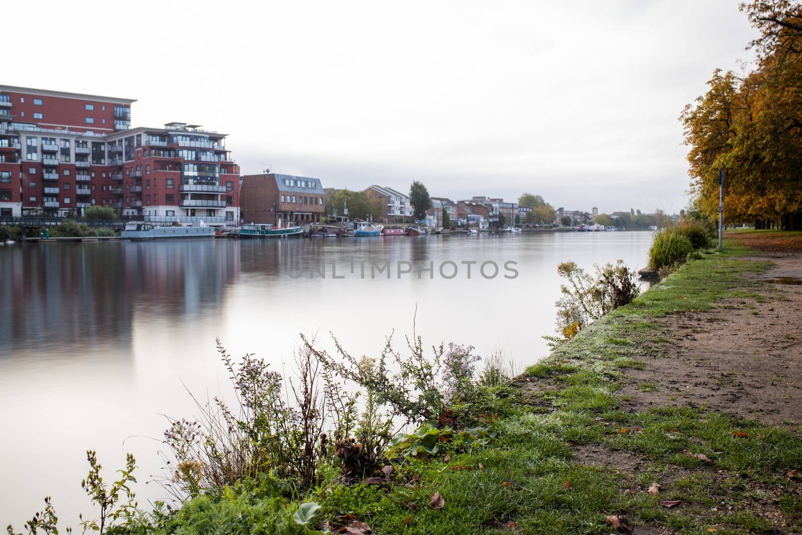 Landscape Picture of a River under a cloudy sky and with Buildings from the Other Side reflecting on the water