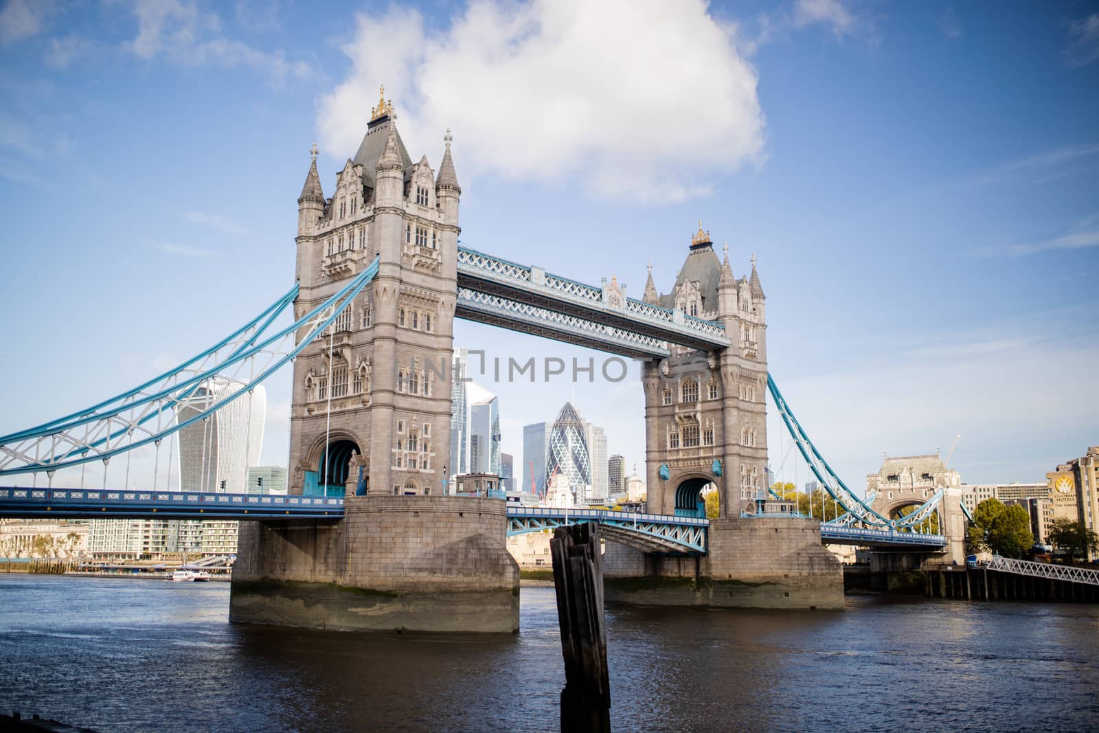 Landscape View of the Tower Bridge -inaugurated in 1894- over the River Thames, under a blue sky and with a Cityscape as background