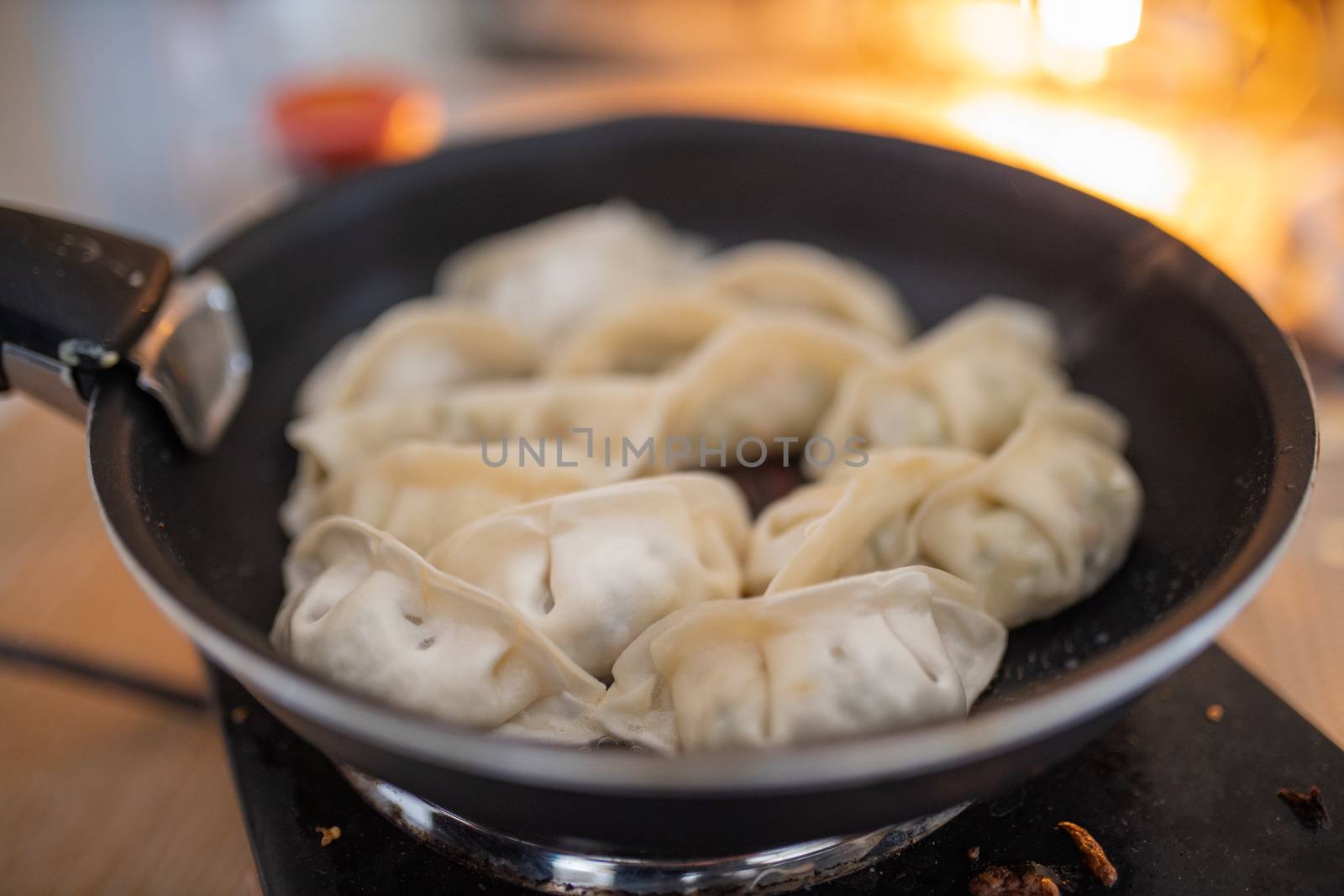 Picture of several Dumplings on a Frying Pan with a Blurry Fireplace in the Background