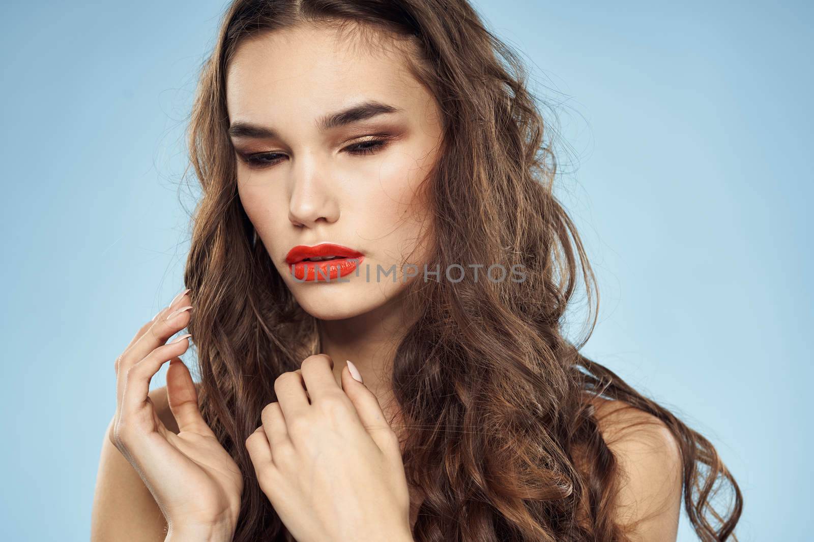 Elegant brunette fashionable hairstyle bright makeup naked shoulders close-up blue background. High quality photo