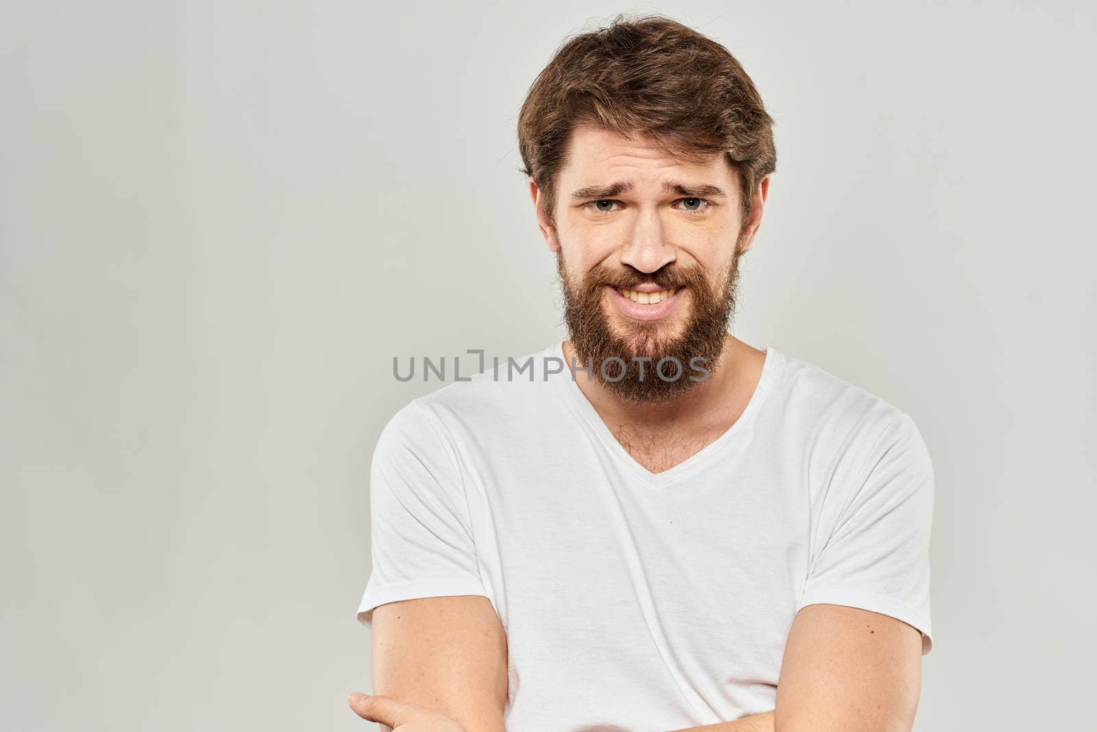 man in white t-shirt gesturing with his hands studio dissatisfaction lifestyle light background. High quality photo