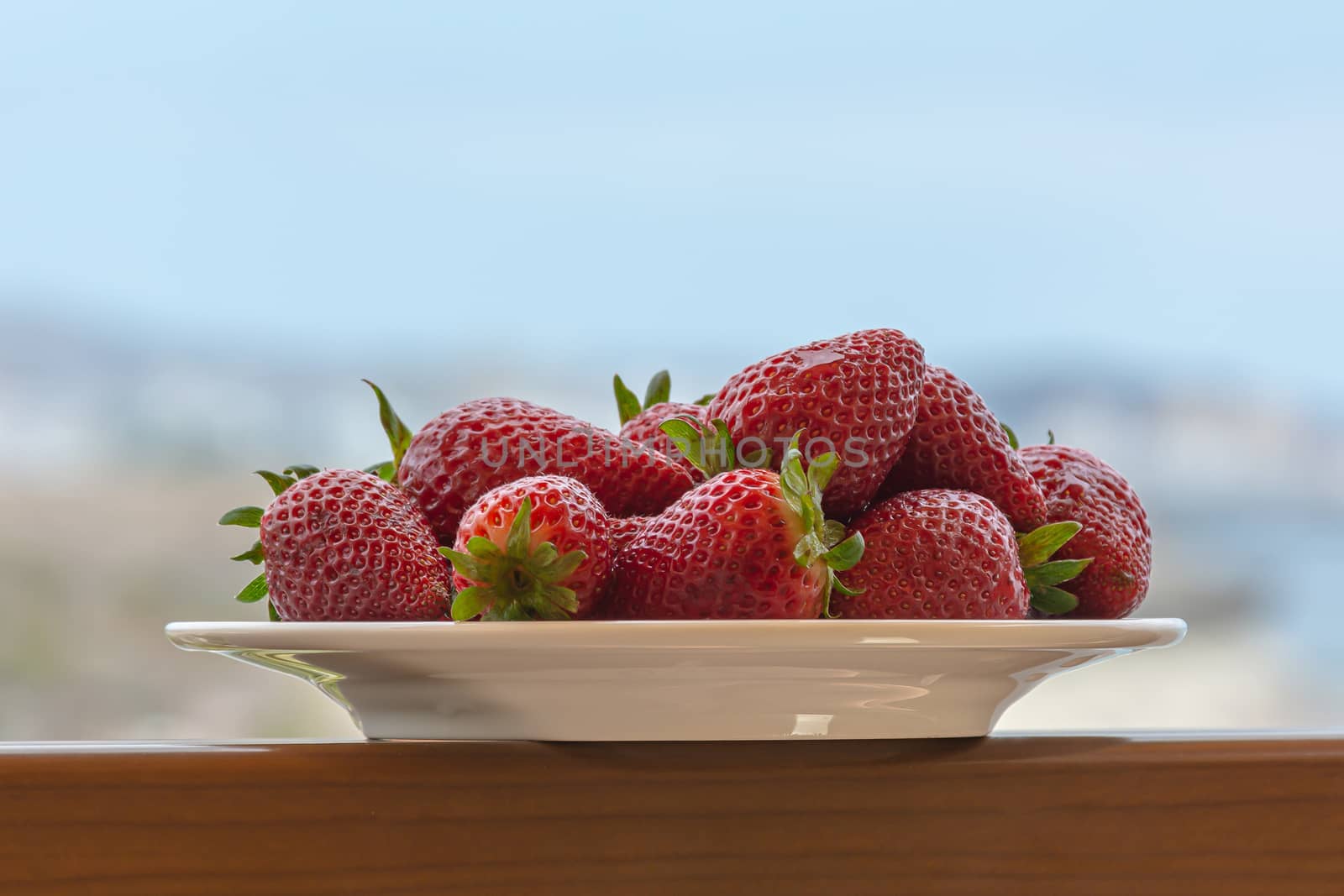 Red ripe strawberries on a plate. Blurry background, close-up. Stock photo