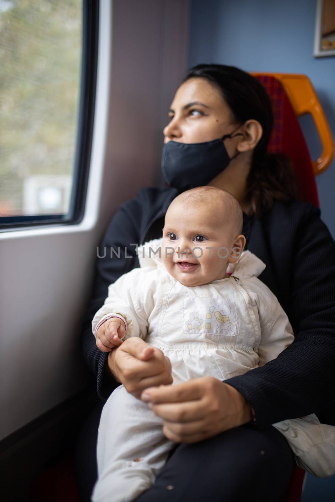 Woman looking through the window of a bus and holding her smiling baby by Kanelbulle