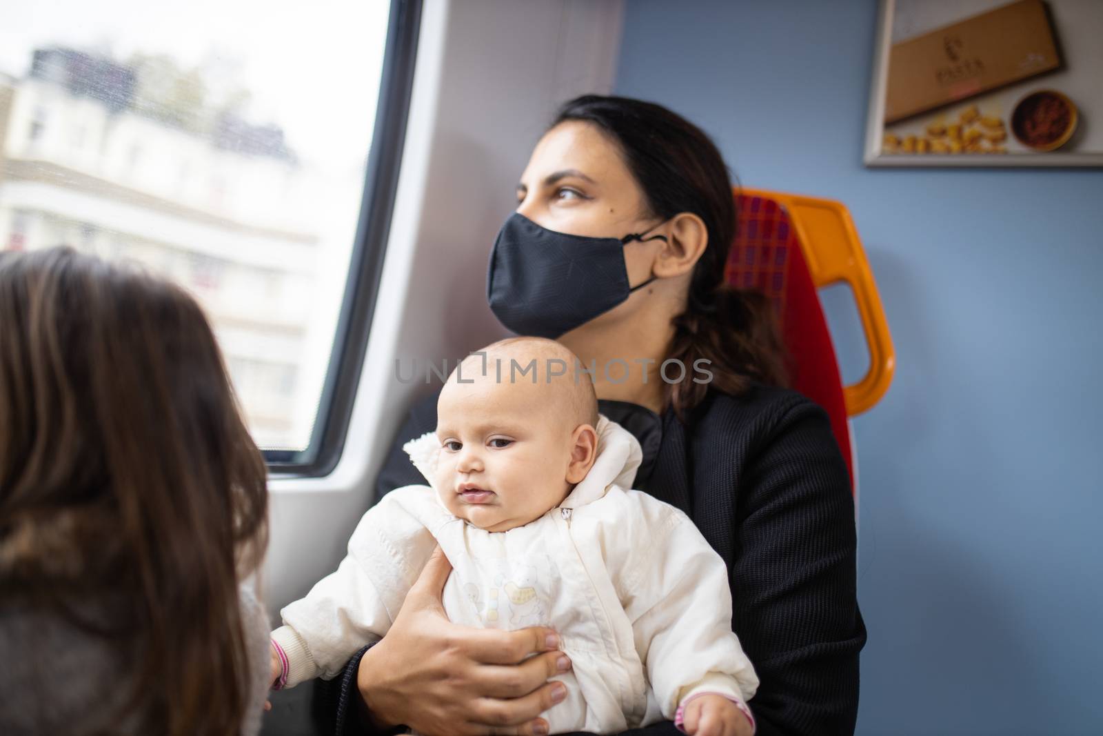 Woman looking through the window of a bus and sitting alongside her daughters by Kanelbulle