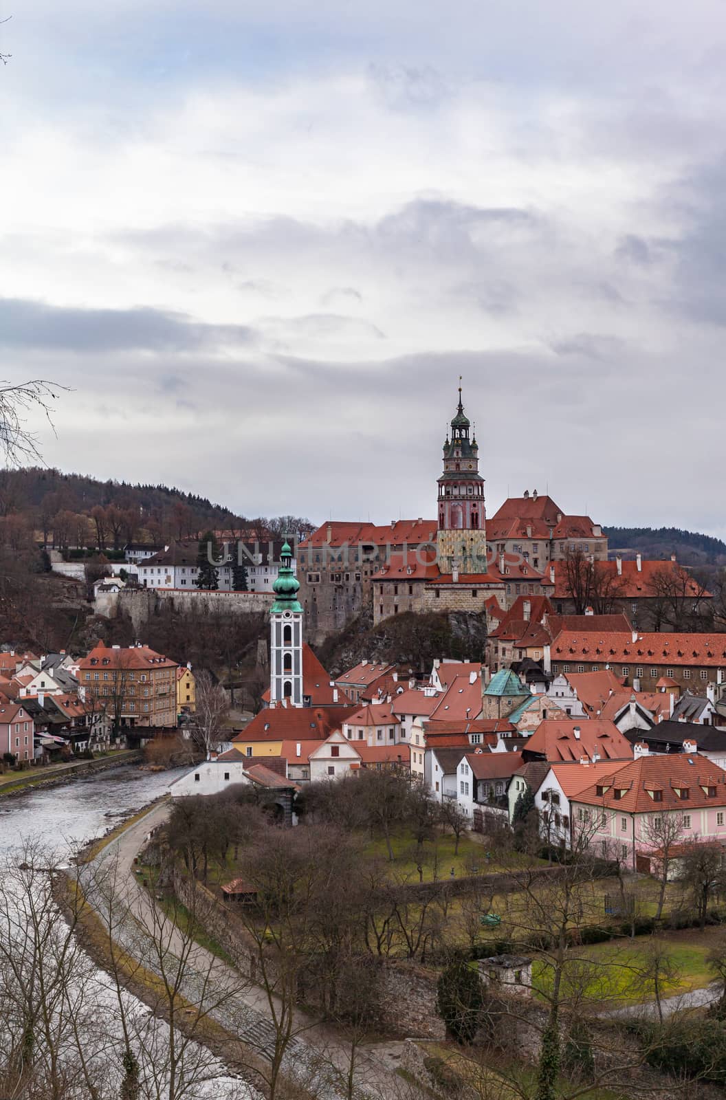 Beautiful aerial of Český Krumlov old town with the Cesky Krumlov castle and tower in background and Vltava river flowing around on a cloudy day, Czech Republic