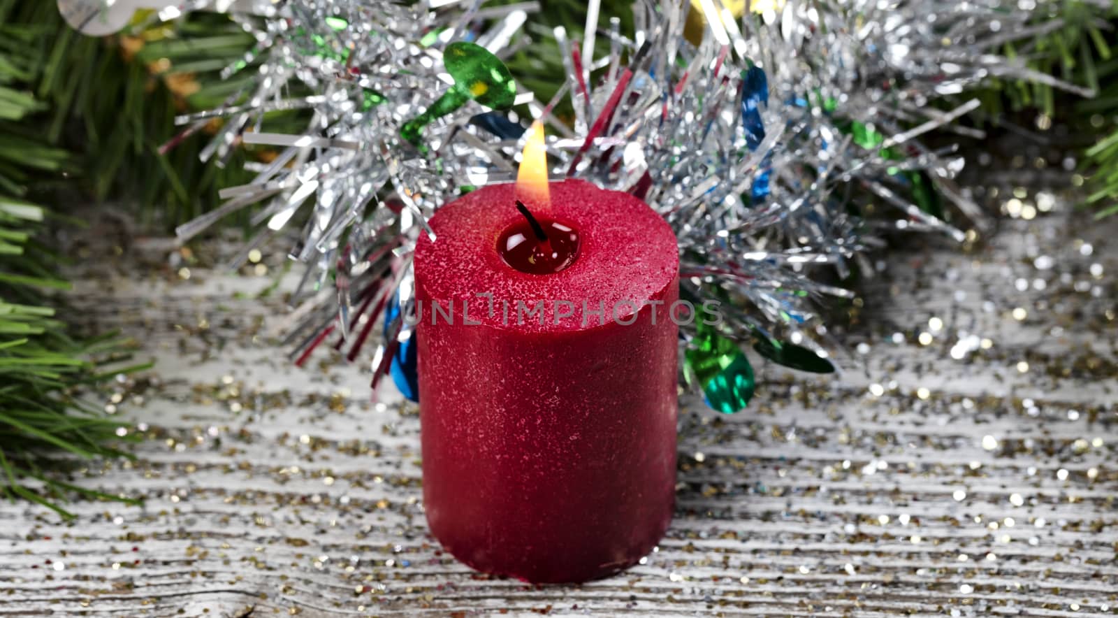 Close up a burning red candle surrounded with Christmas Decorations 