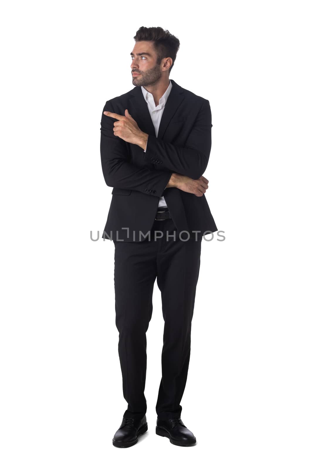 Full length portrait of young handsome business man in black suit pointing showing copy space studio isolated on white background