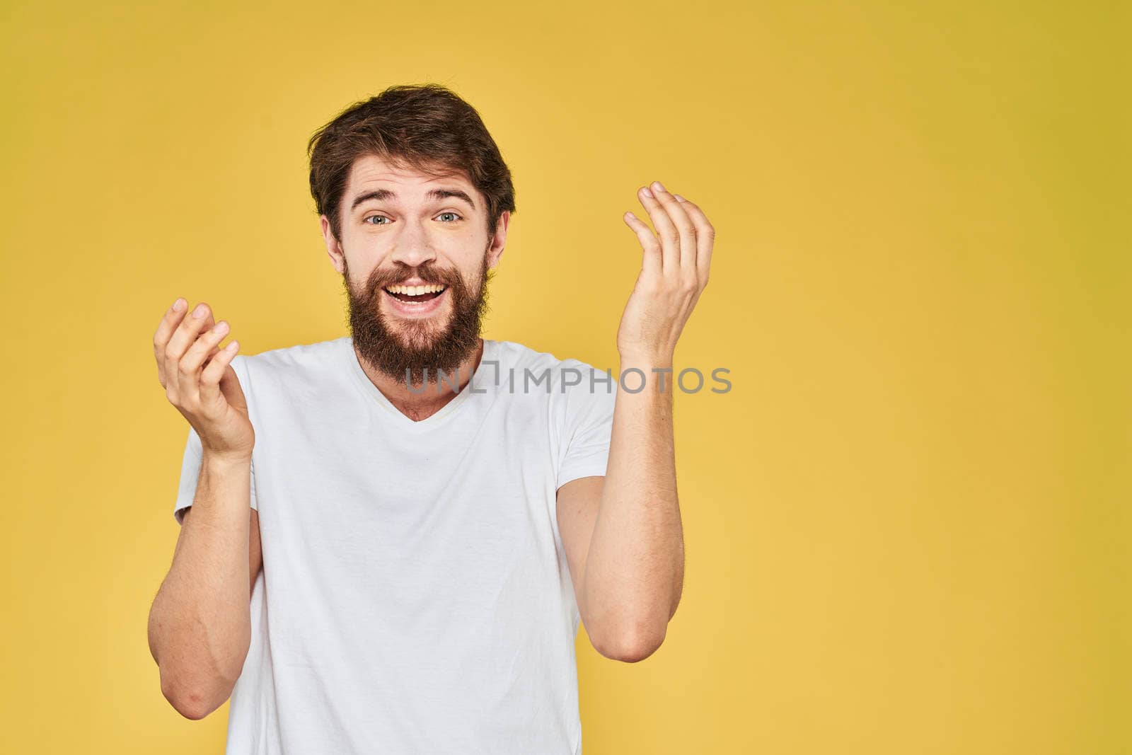 Bearded man white t-shirt emotions gestures with hands fun yellow background. High quality photo