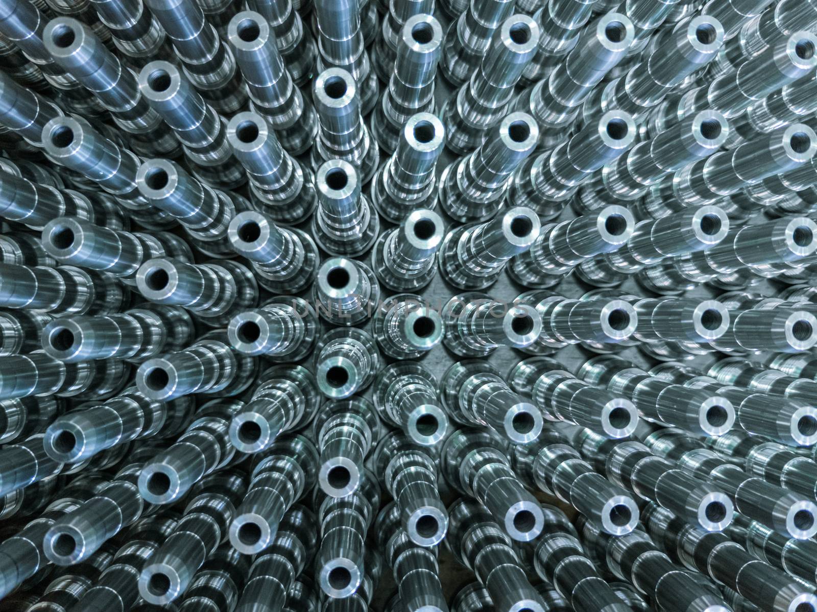 Shiny long steel parts full frame background, clean steel threaded rods after fine cnc turning. Standing vertically in a rows with selective focus in directly above perspective.