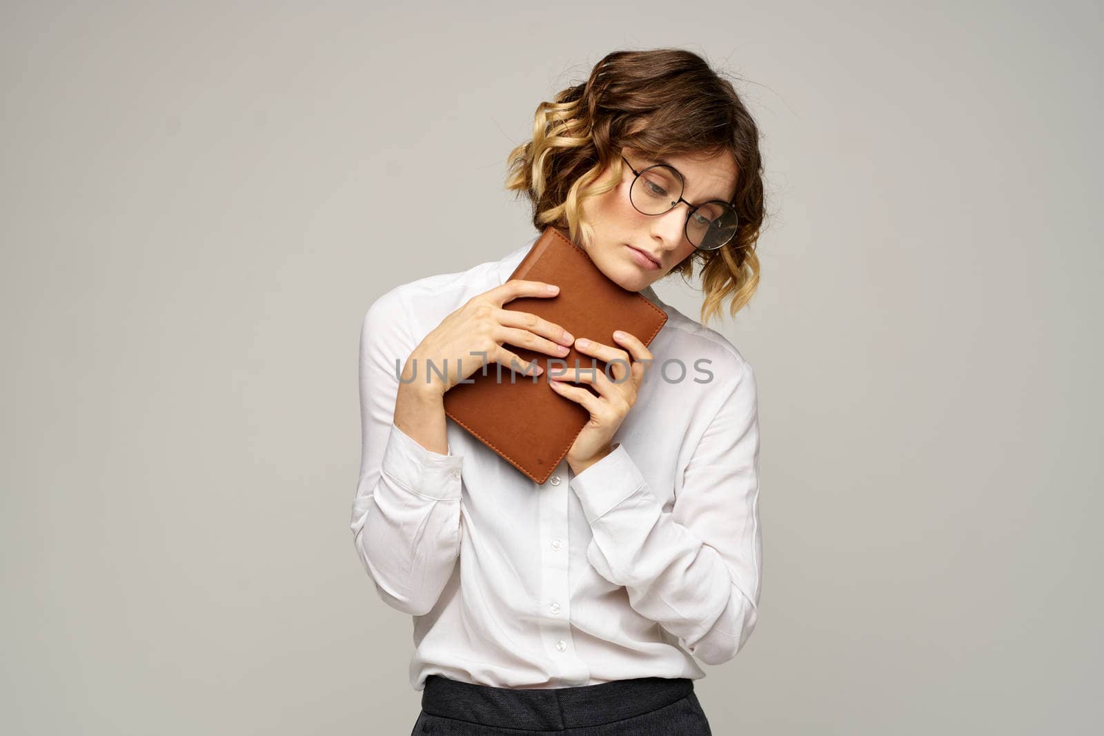 Business woman with notepad and glasses on a light background hairstyle success emotions. High quality photo