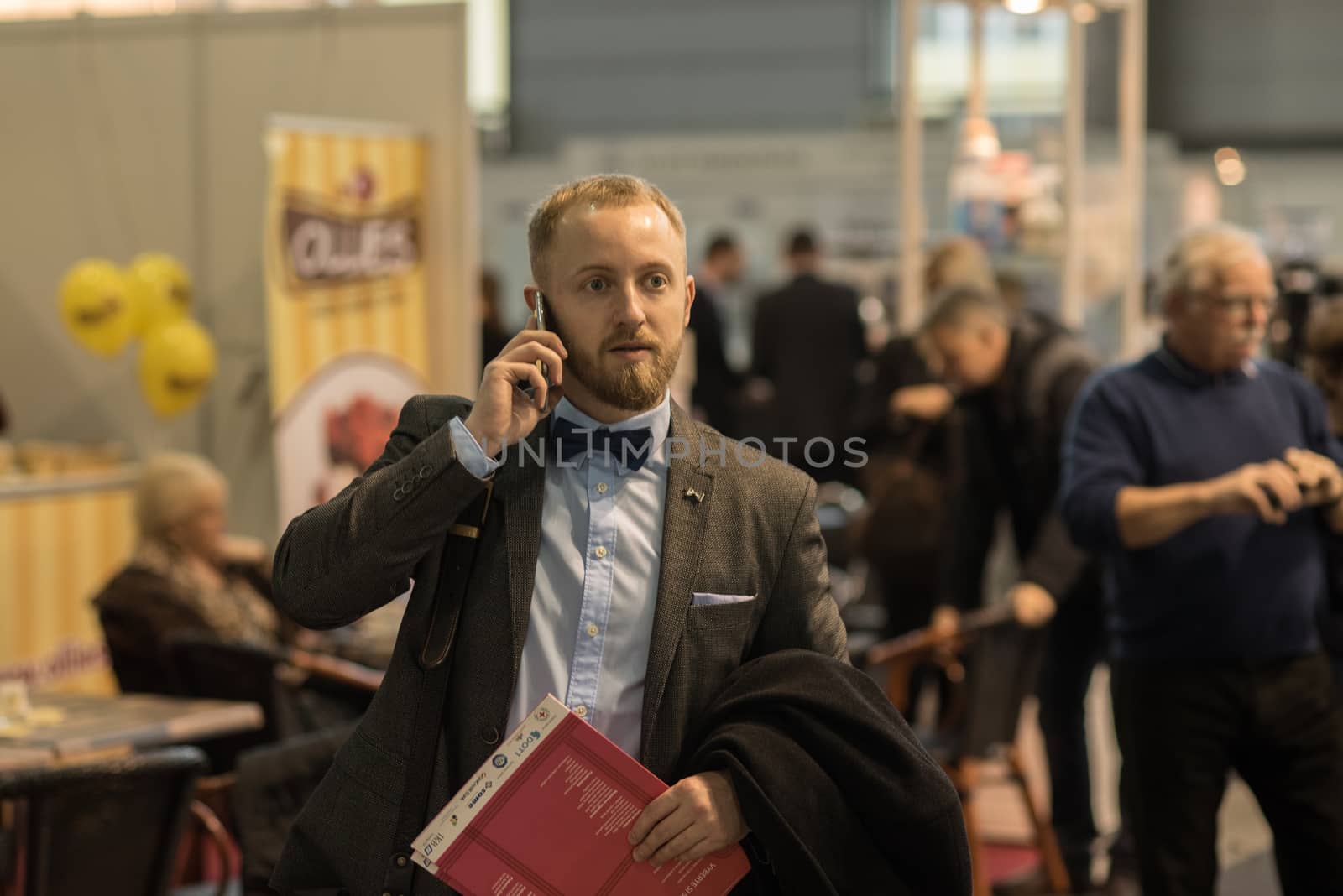 A man is walking while speaking on the phone at the convention trade center in Brno taking some time to have a coffee. BVV Brno Exhibition center. Czech Republic